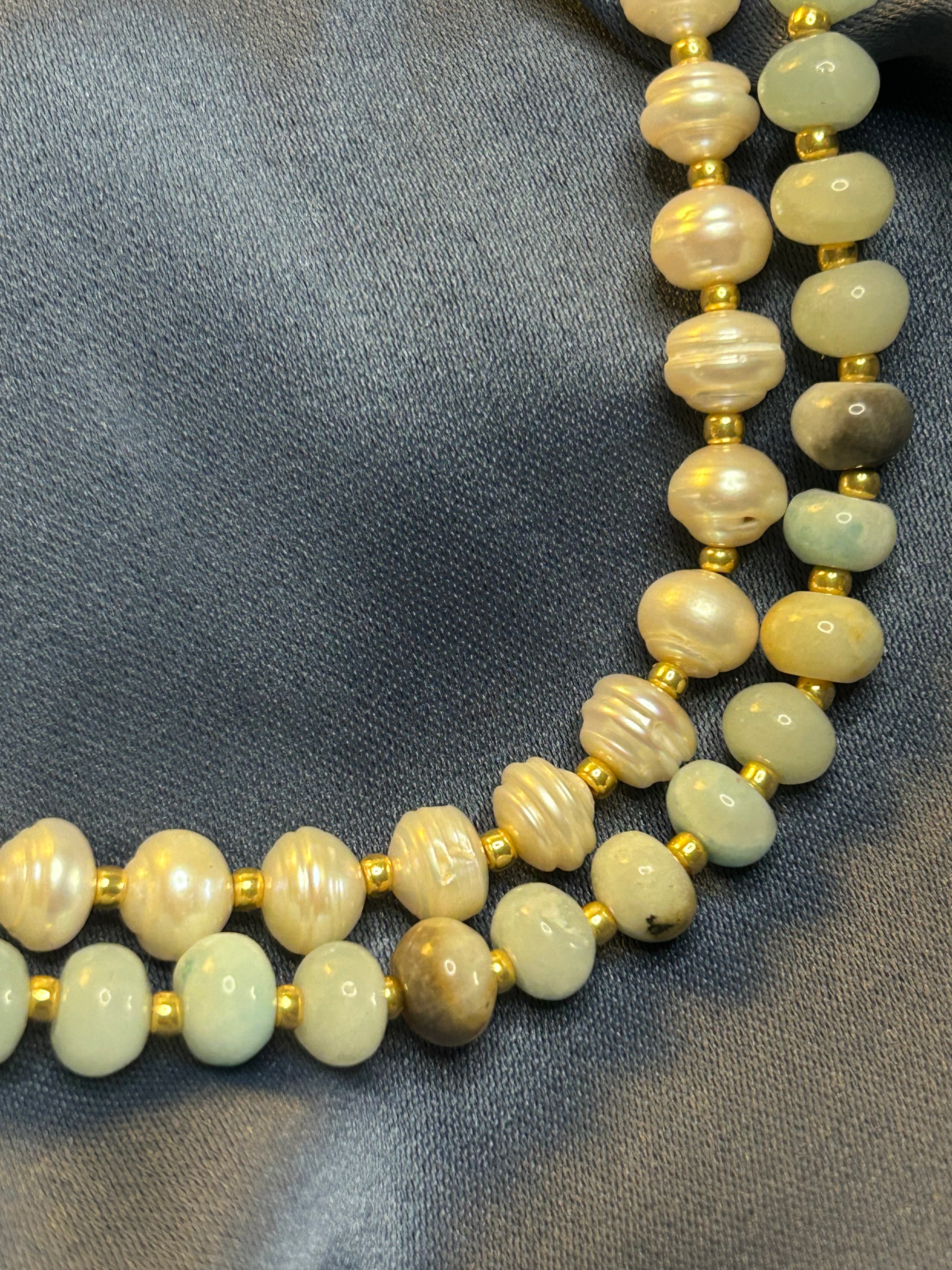 Necklace with green beads and gold accents on a gray fabric background
