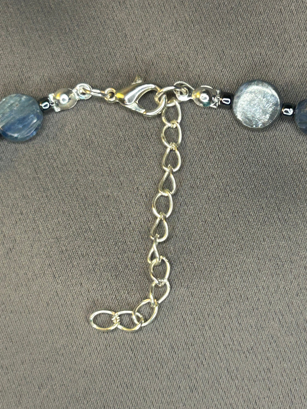 Silver necklace with blue beads on a gray background