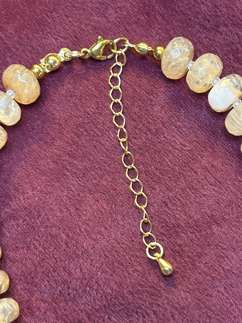 Necklace with gold chain and beige beads on a purple background