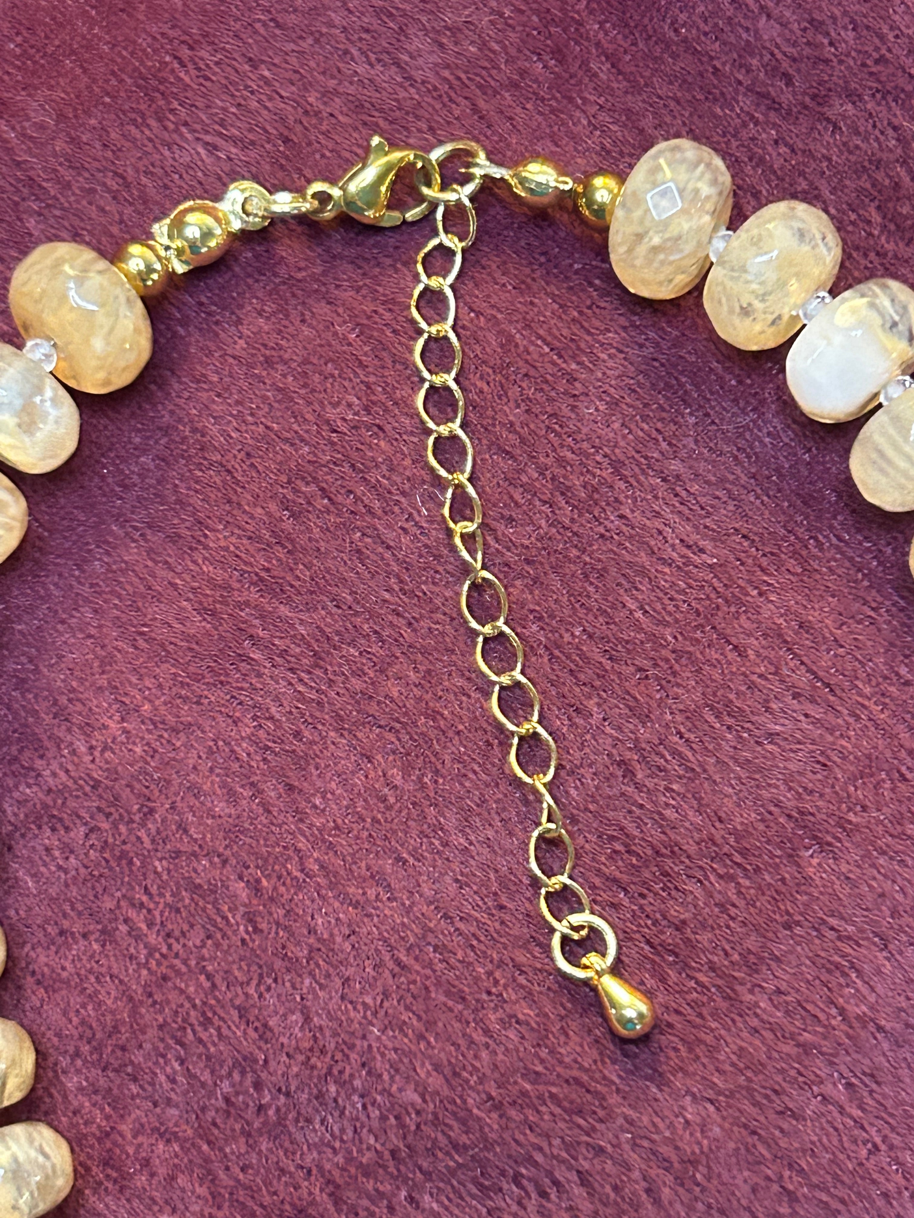 Necklace with gold chain and beige beads on a purple background