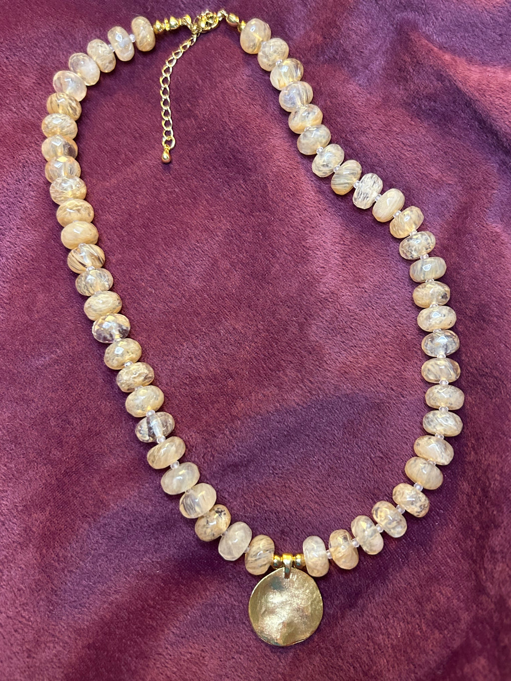 Beaded necklace with a gold clasp on a purple fabric background