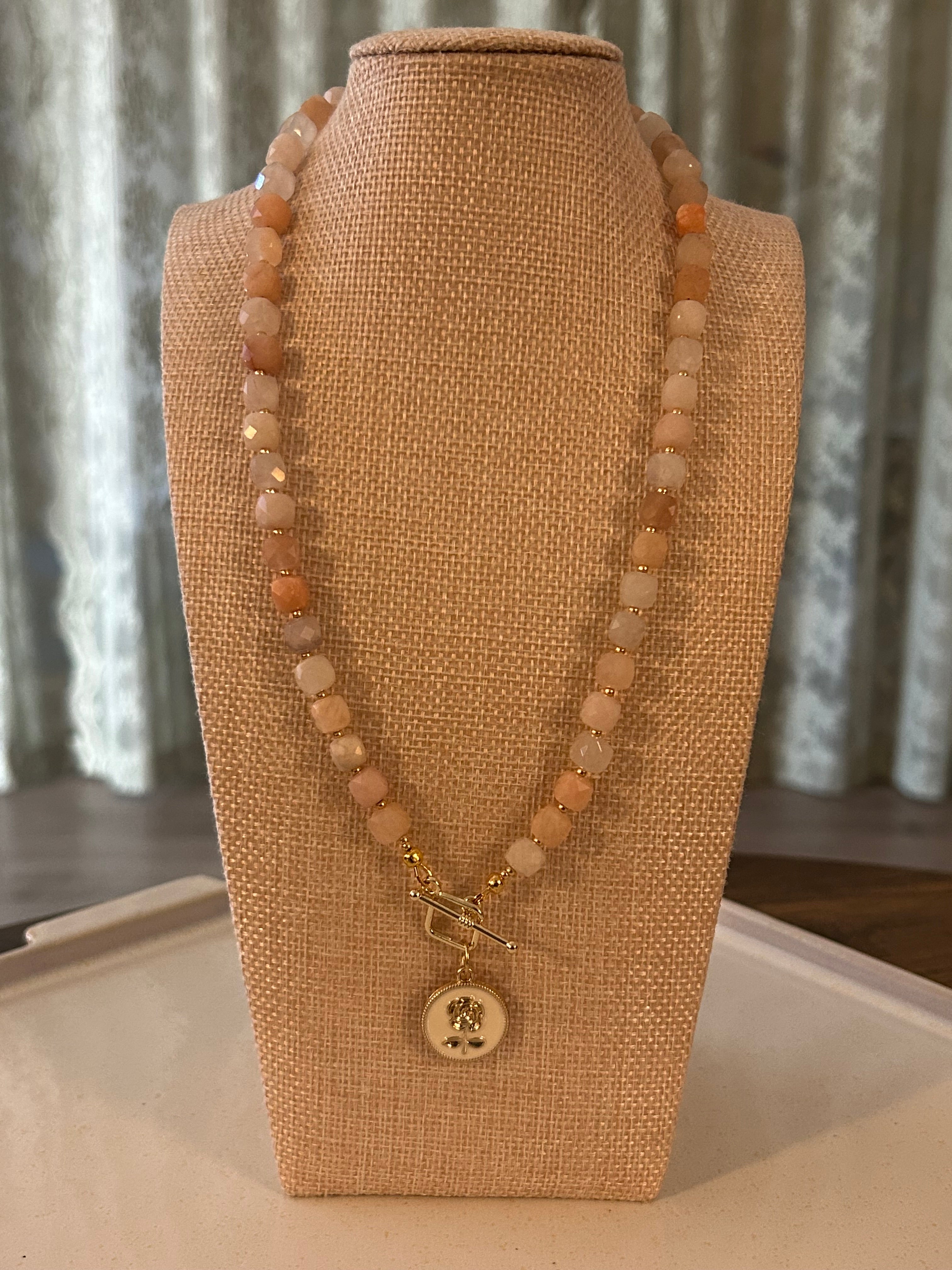 Necklace with square beads on a mannequin bust against a neutral background