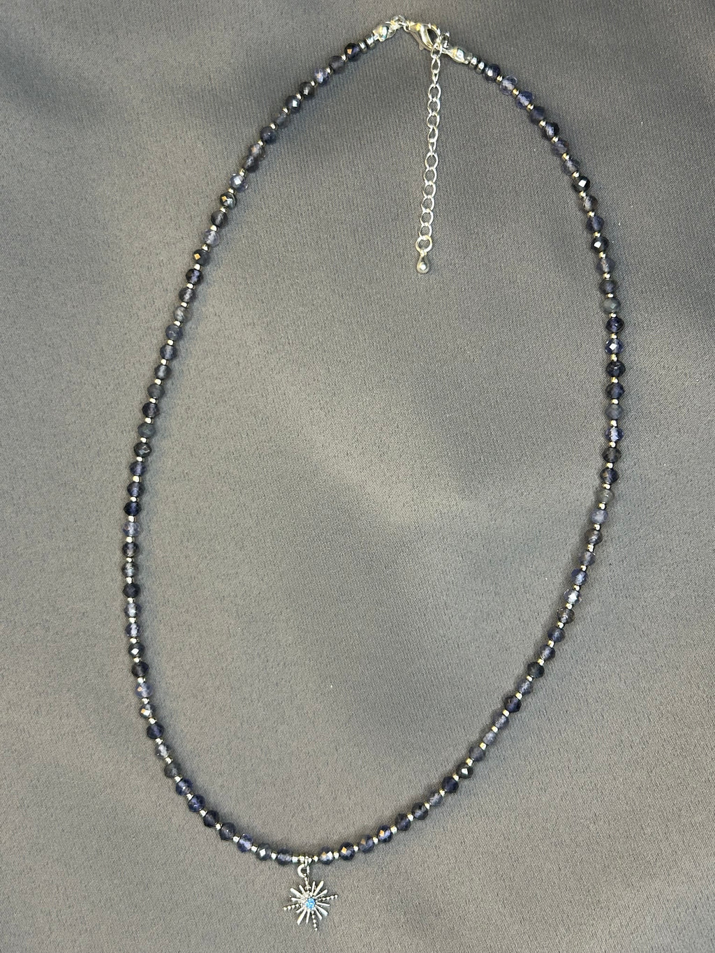 Necklace with blue beads on a gray fabric background