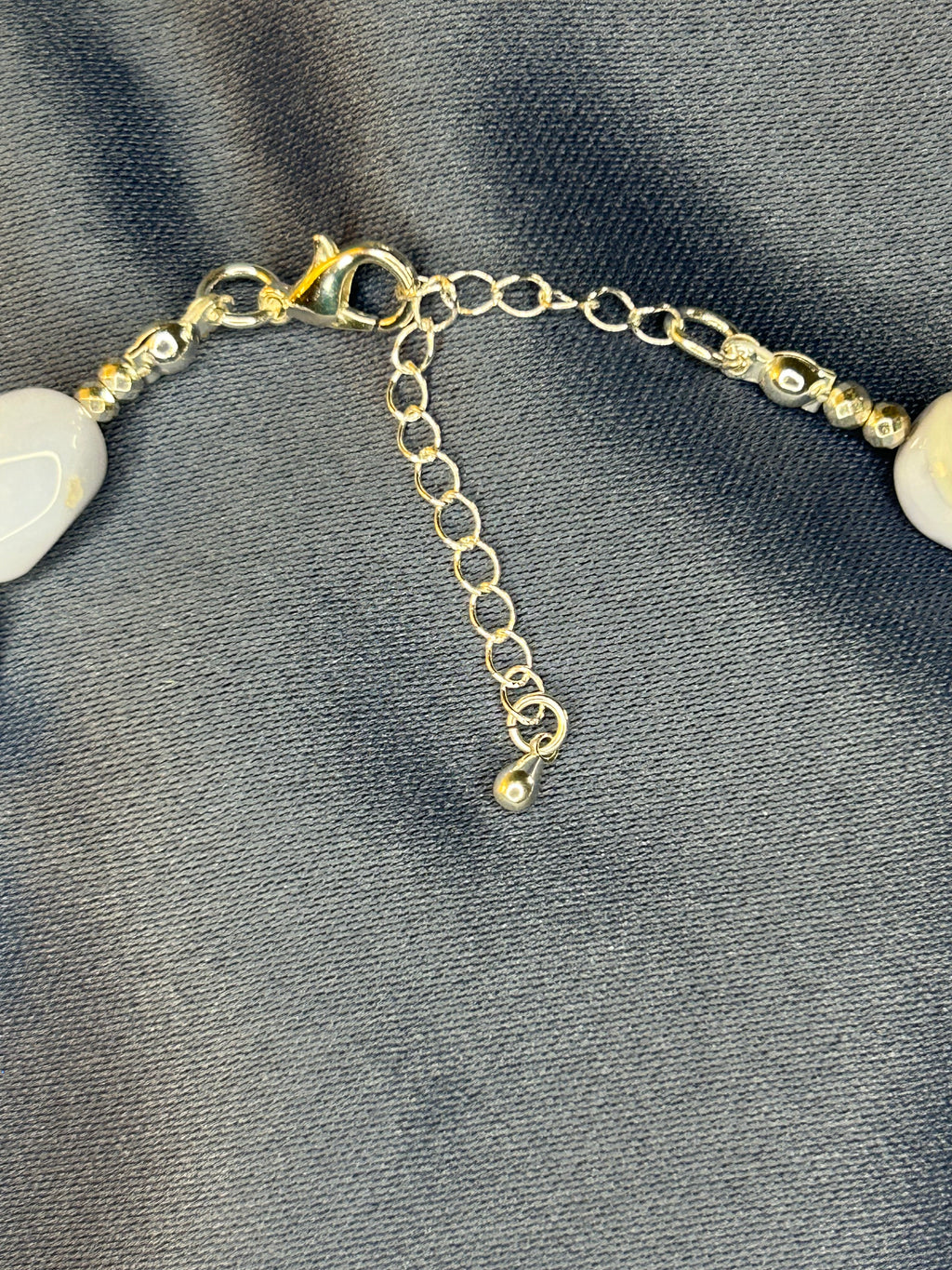 Necklace with blue beads and gold chain on a gray fabric background