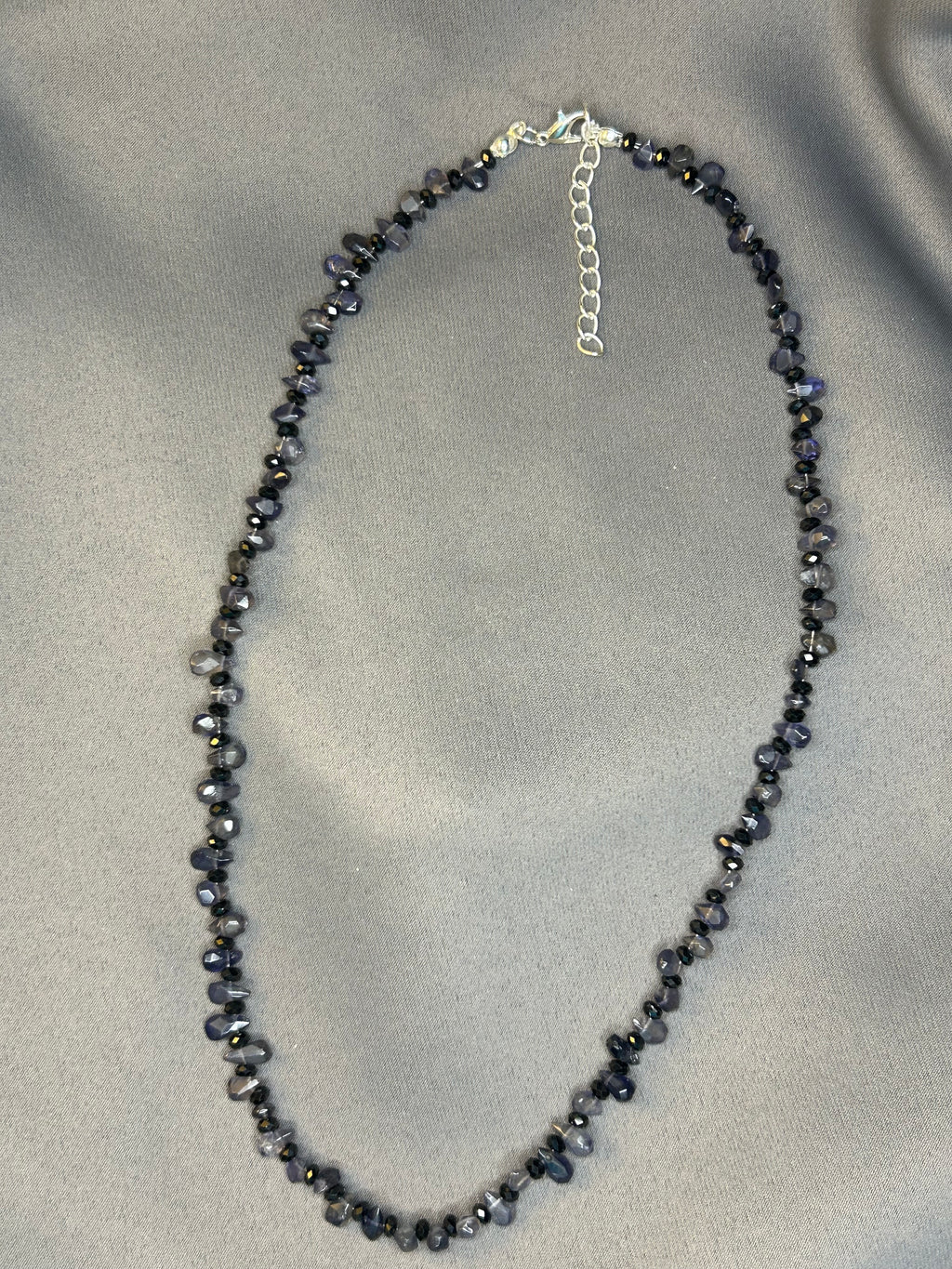 Necklace with dark beads on a light gray fabric background