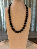 Dark red beaded necklace on a beige display against a neutral background
