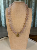 Purple clear beaded necklace on a mannequin bust with a neutral background