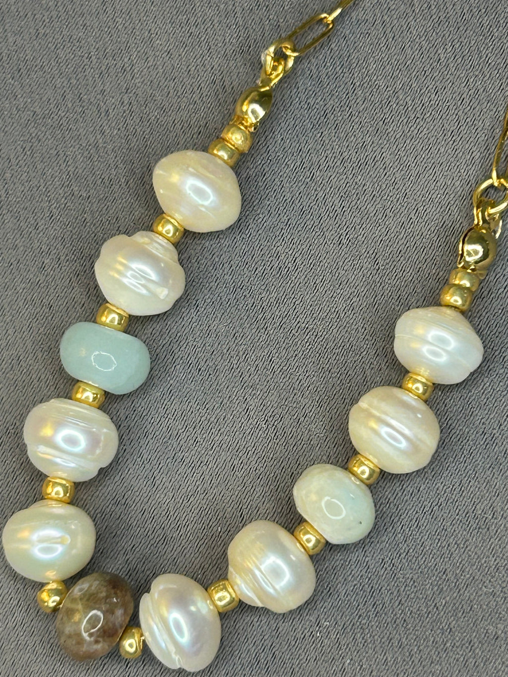 Pearl and gold beaded necklace on a gray background