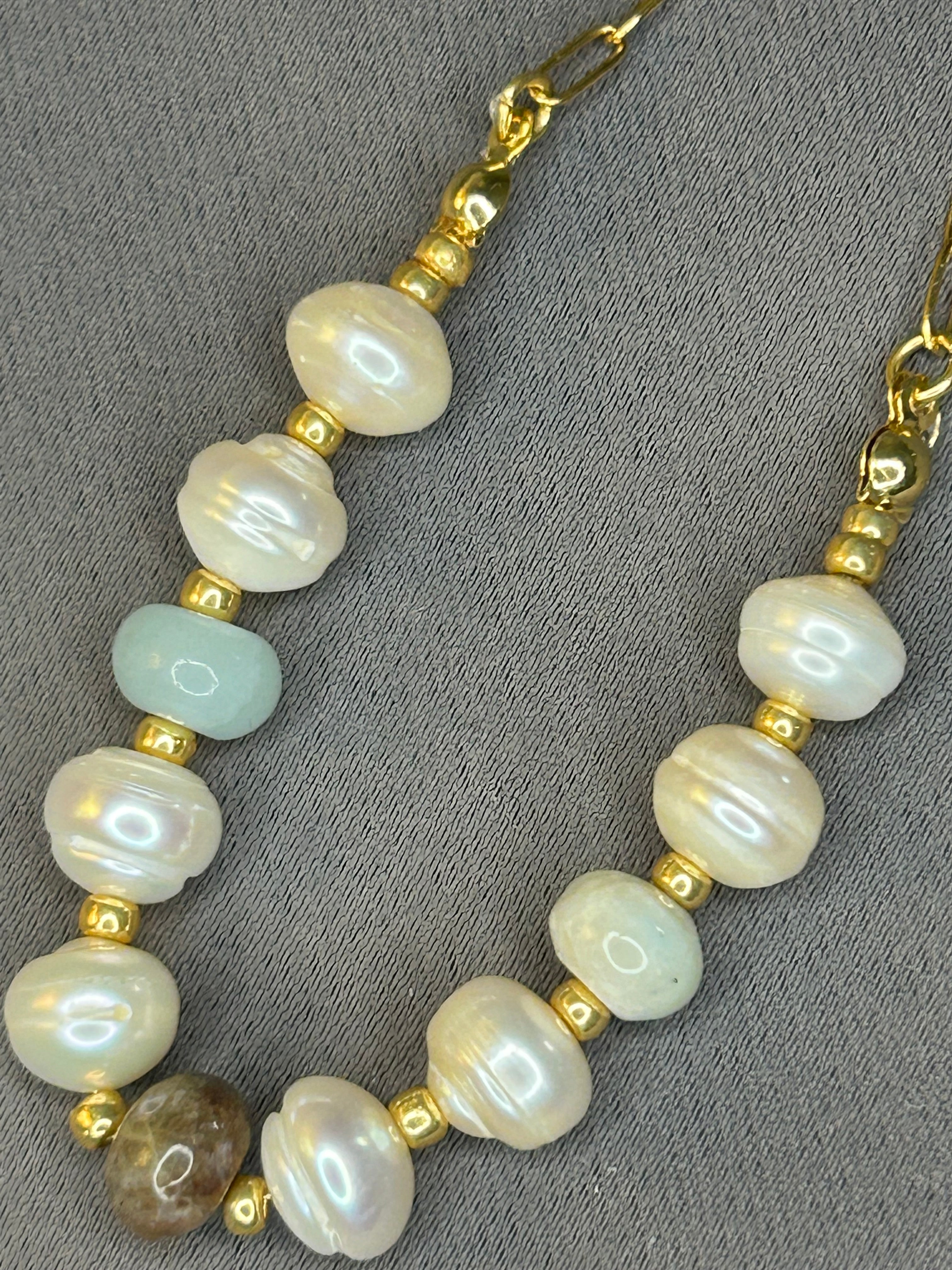 Pearl and gold beaded necklace on a gray background