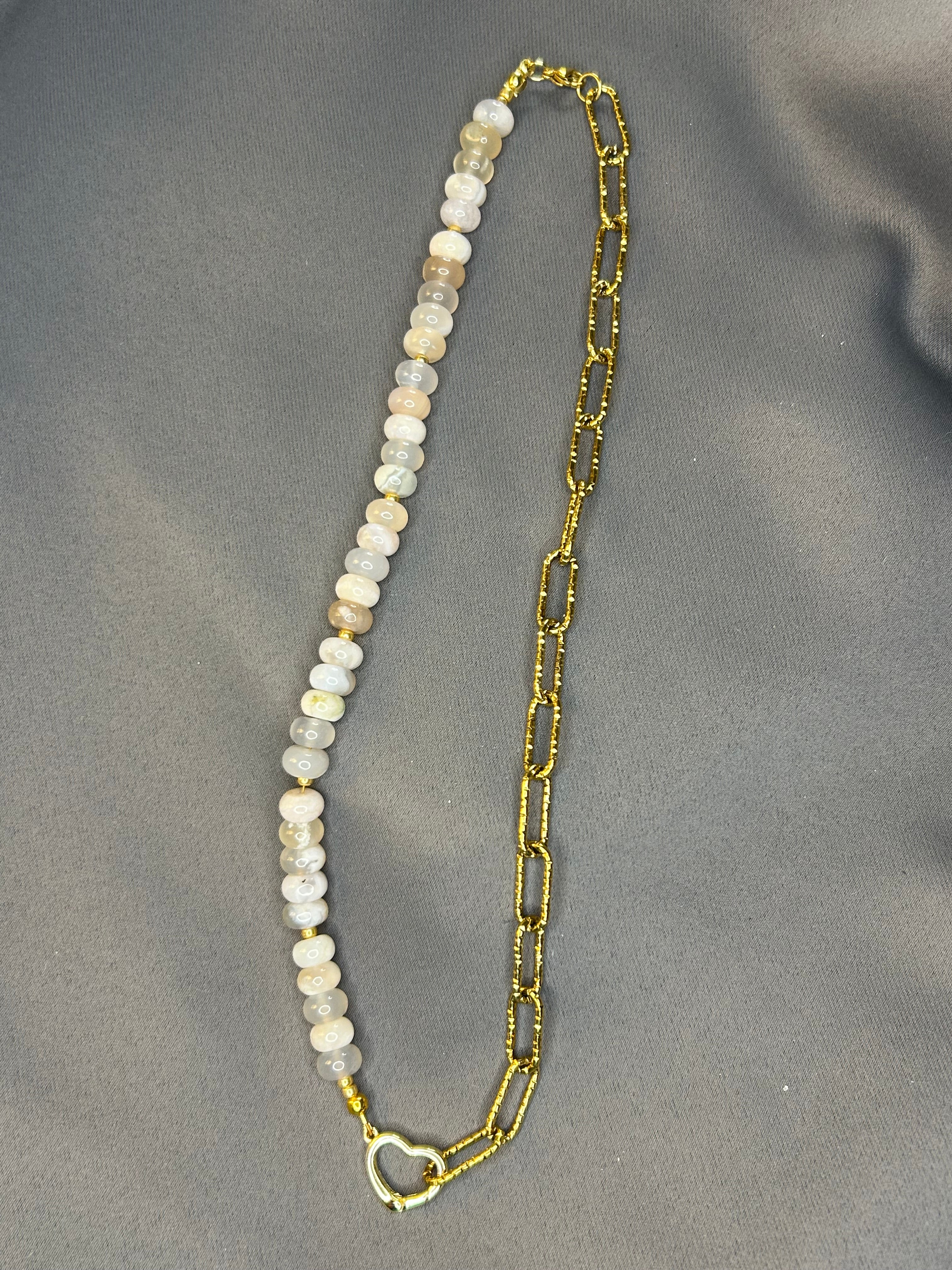 Necklace with gold chain and white beads on a gray background