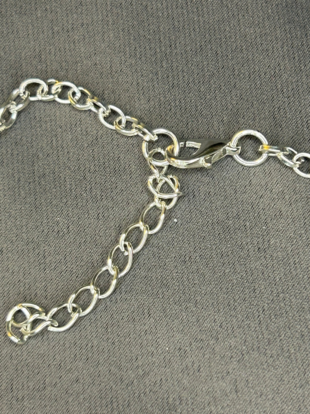 Silver chain with a clasp on a gray textured background