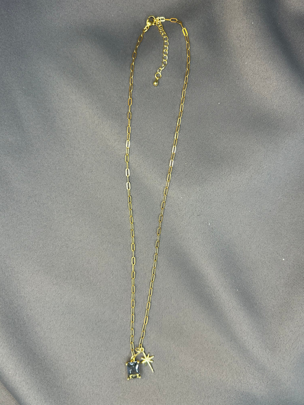 Gold necklace with a star pendant on a gray fabric background