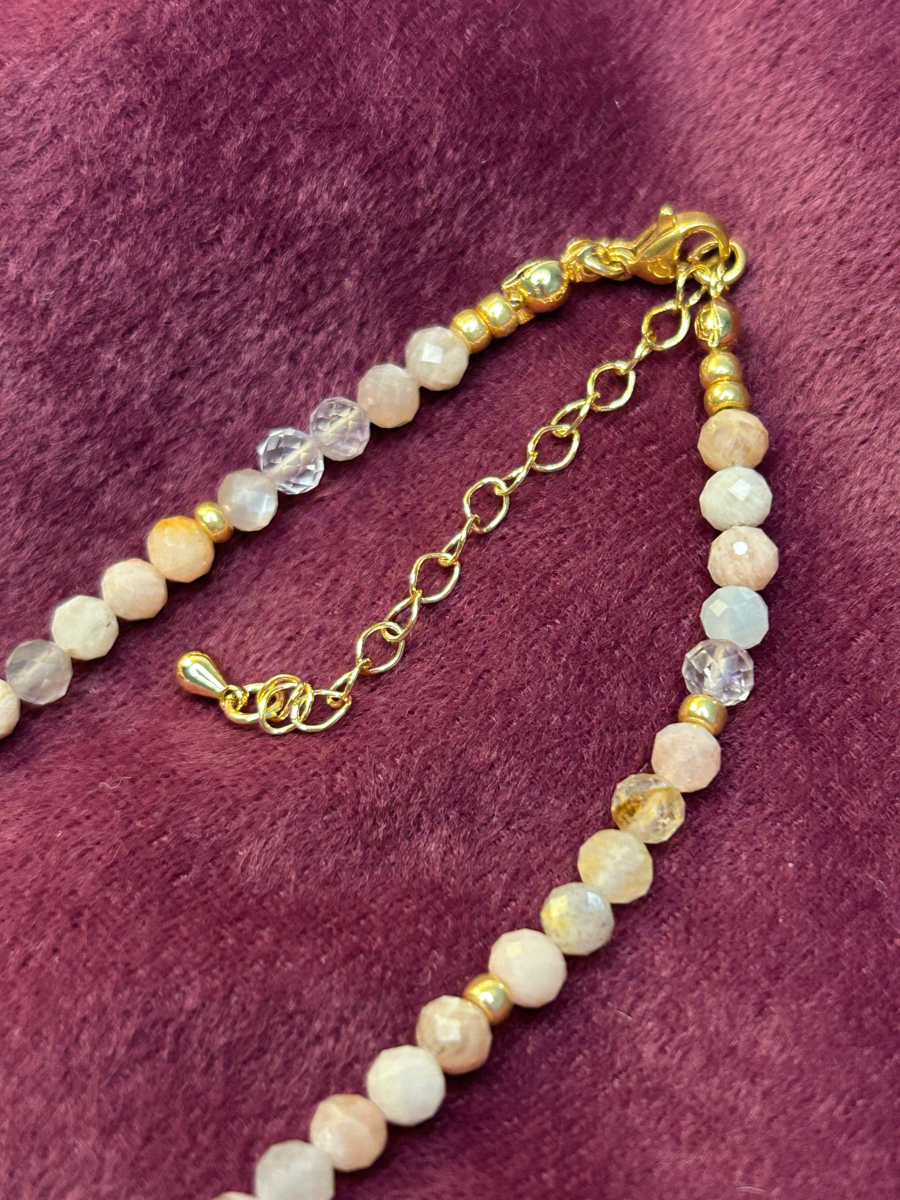 Beaded necklace with gold chain on a purple fabric background