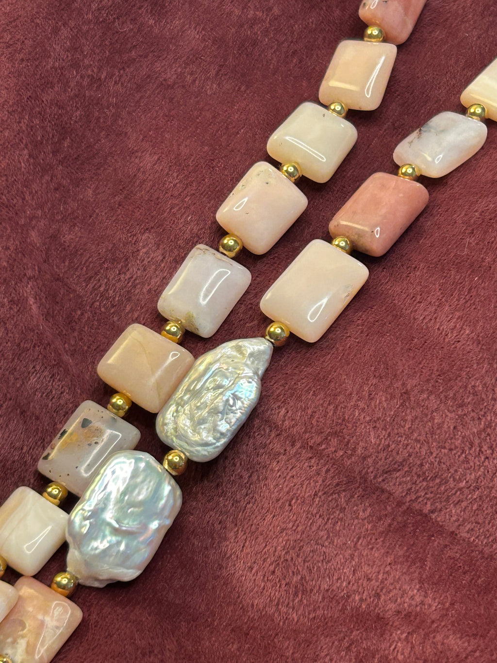 Necklace with pink and white beads on a maroon fabric background
