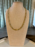 Gold beaded necklace on a mannequin bust against a neutral background