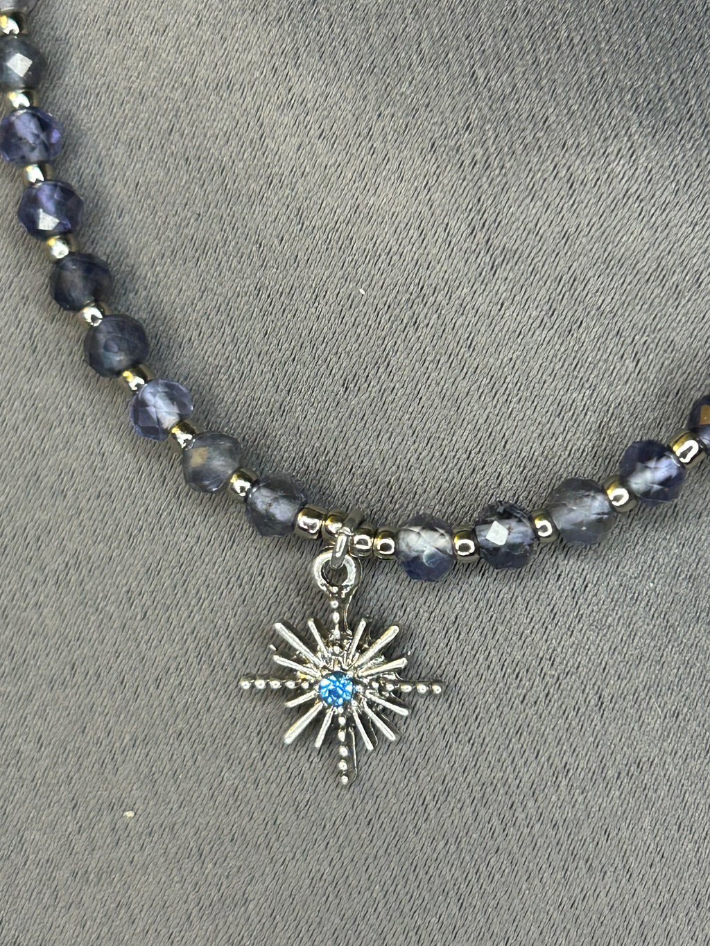 Necklace with dark beads and a star charm on a gray background