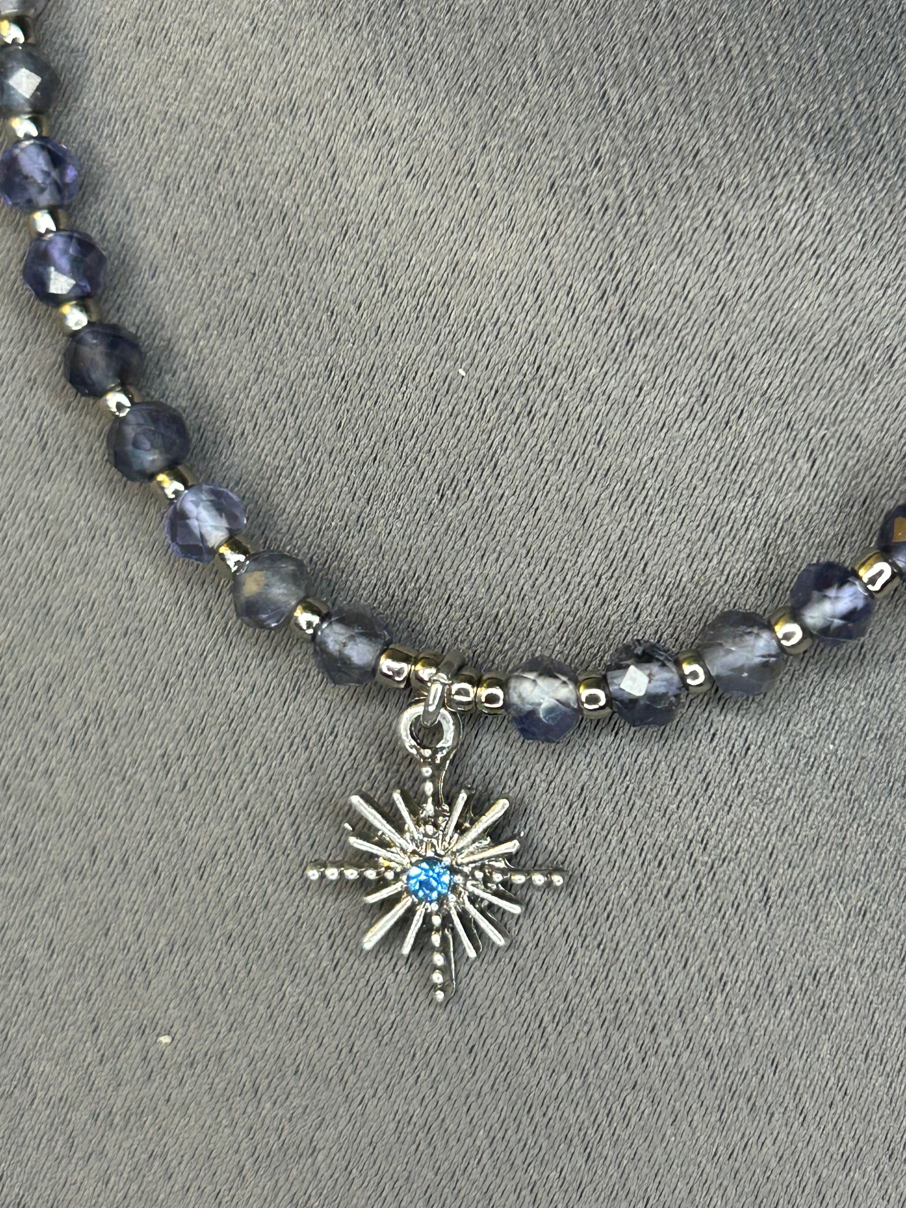 Necklace with dark beads and a star charm on a gray background