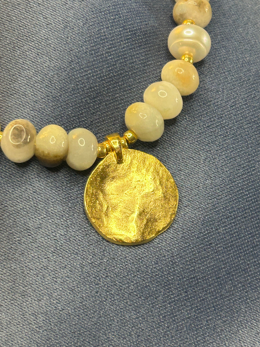 Necklace with beads and a gold disc on a gray background