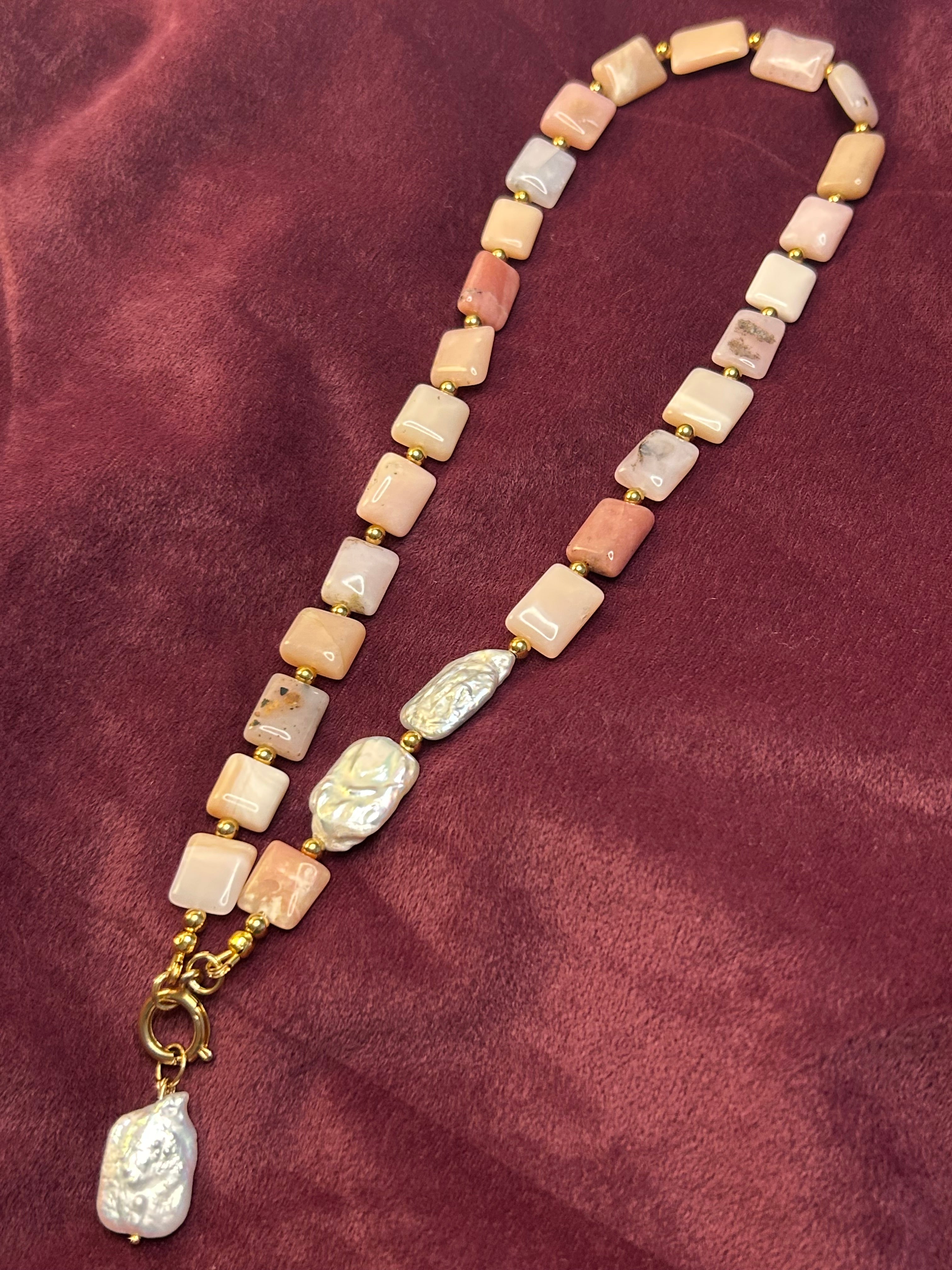 Necklace with square beads and gold chain on a maroon fabric background