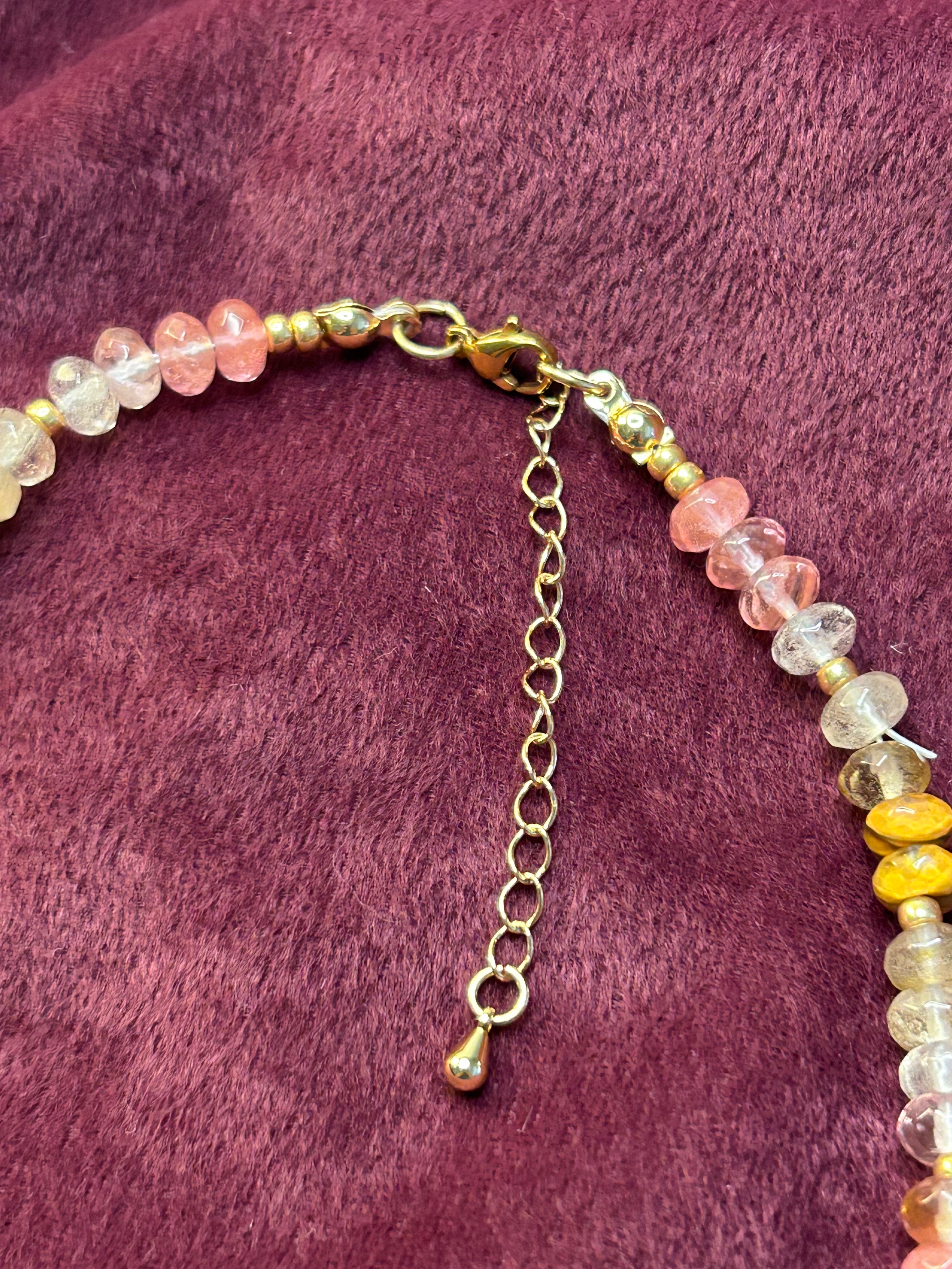 Beaded necklace with a gold chain on a purple fabric background