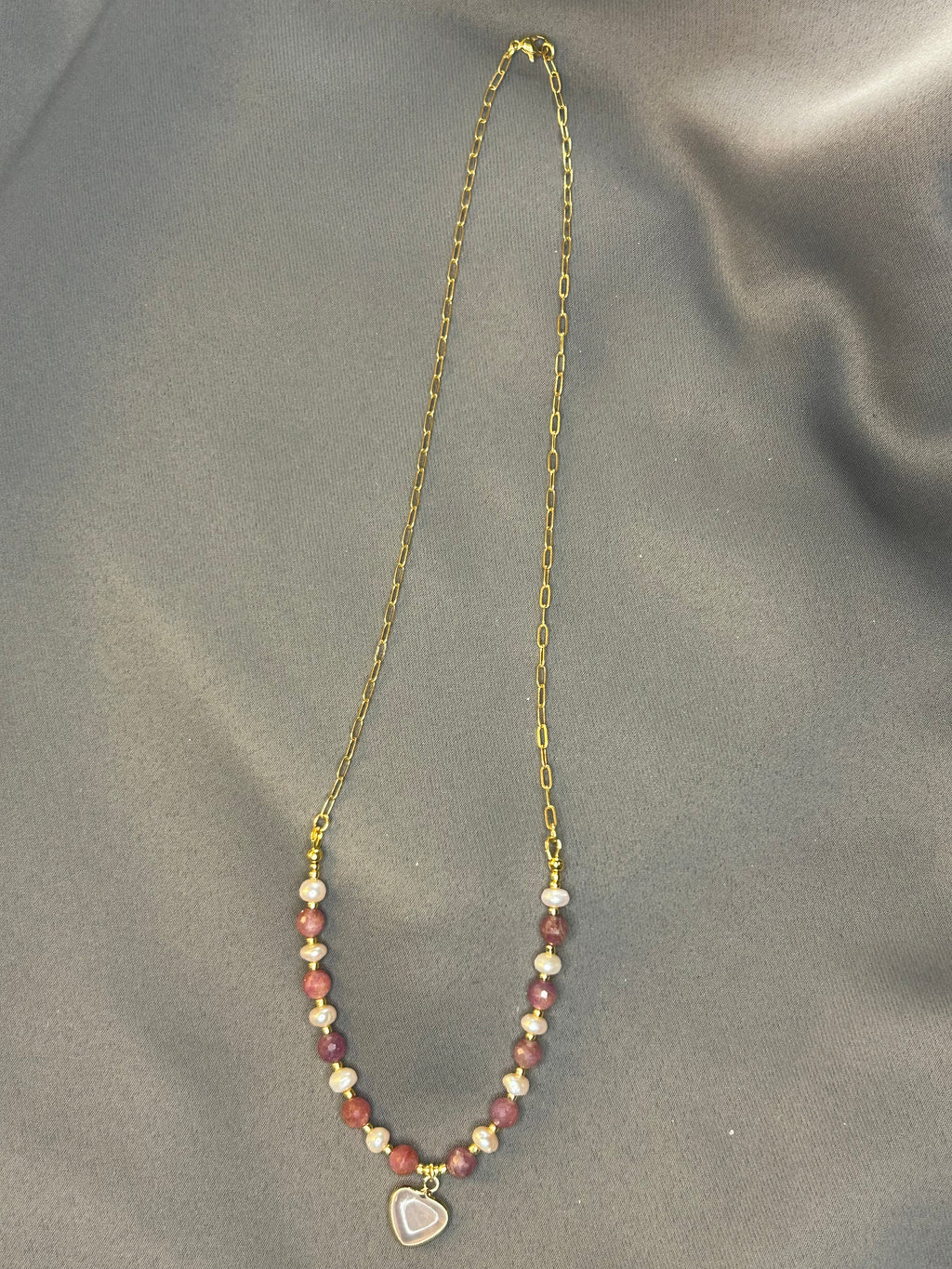 Necklace with heart-shaped pendant on a gray fabric background