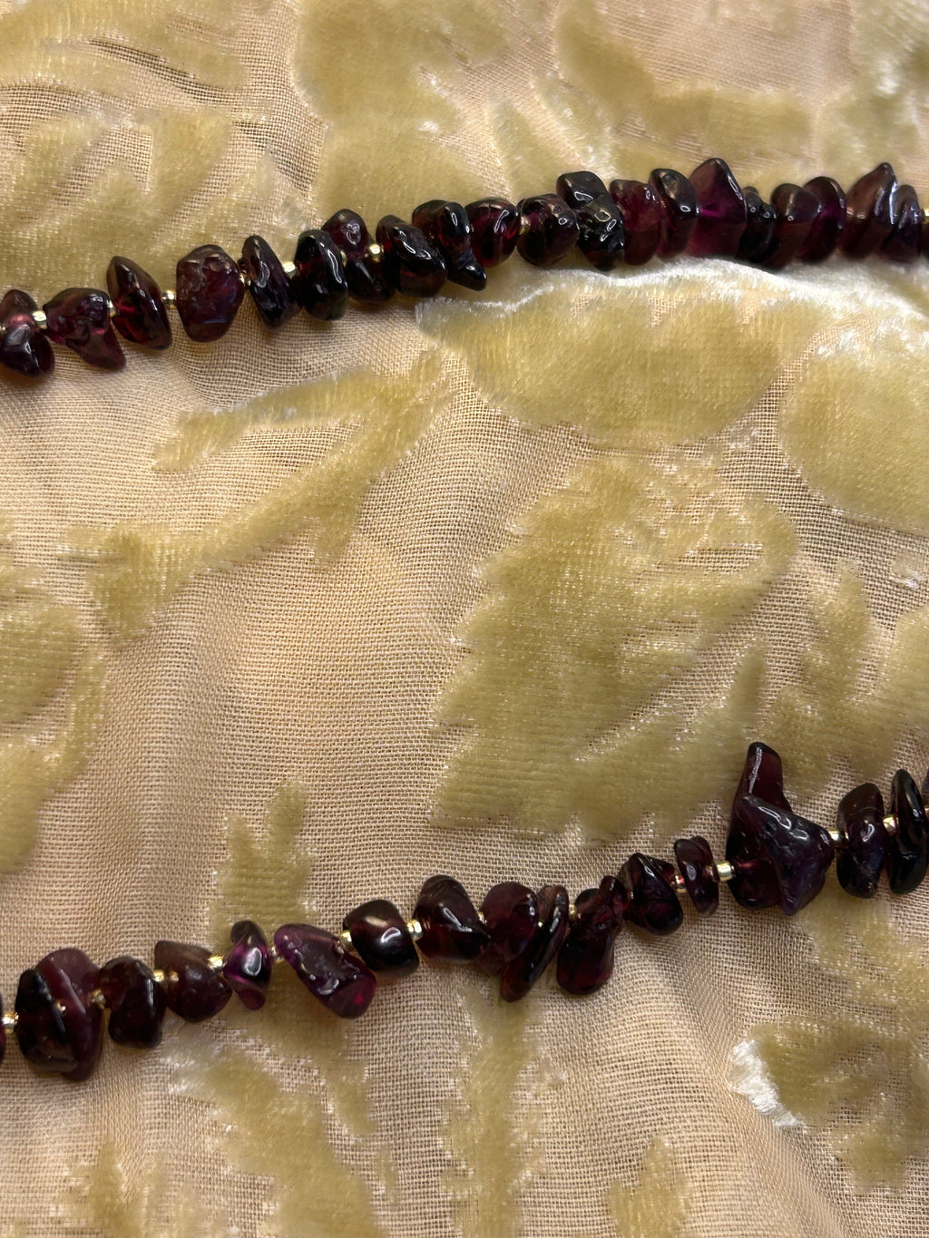 Necklace with dark red beads on a textured beige fabric background
