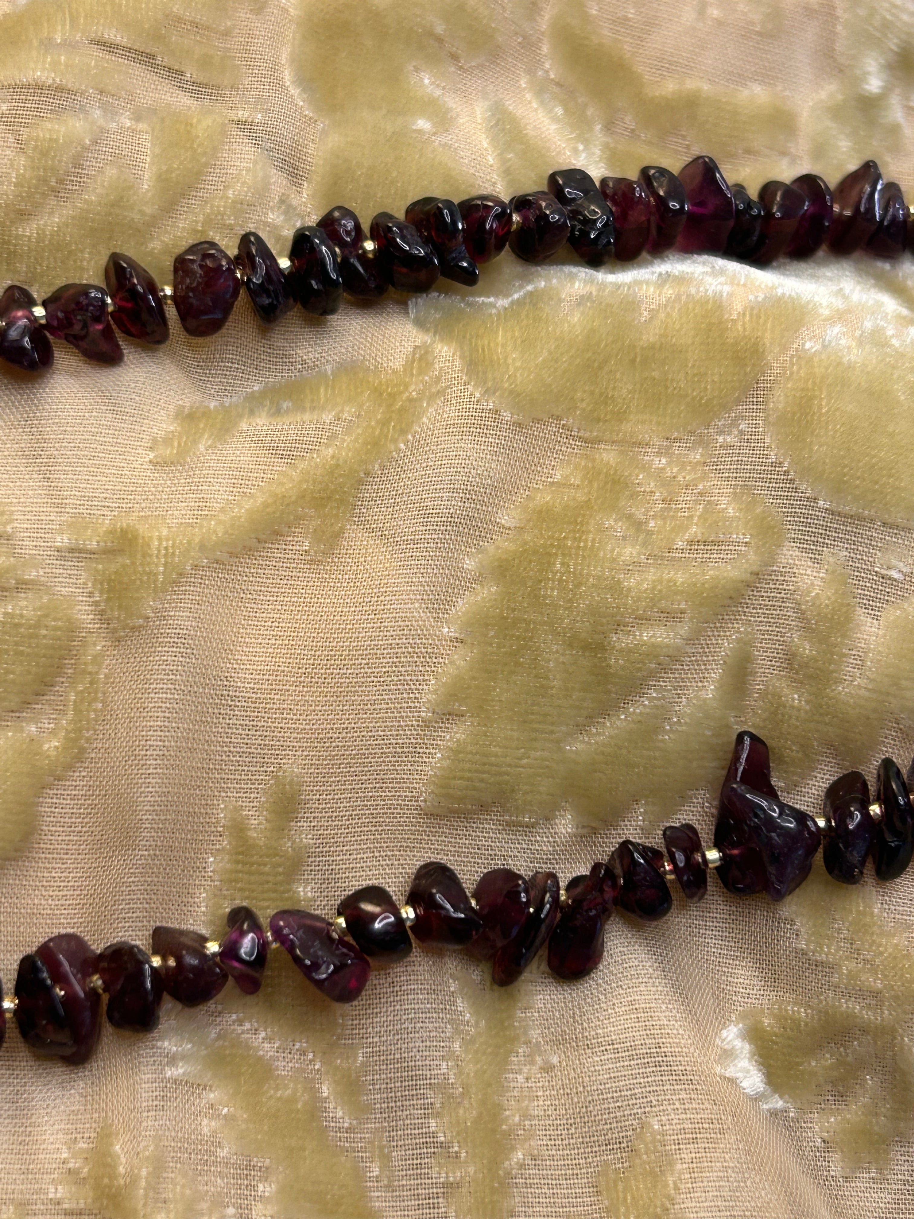 Necklace with dark red beads on a textured beige fabric background