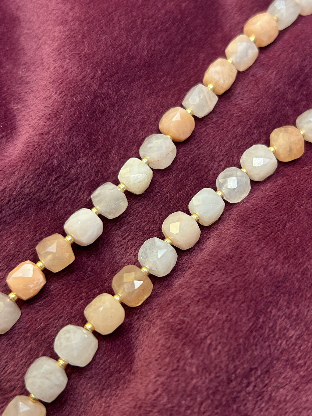 Necklace with beige and white beads on a purple fabric background