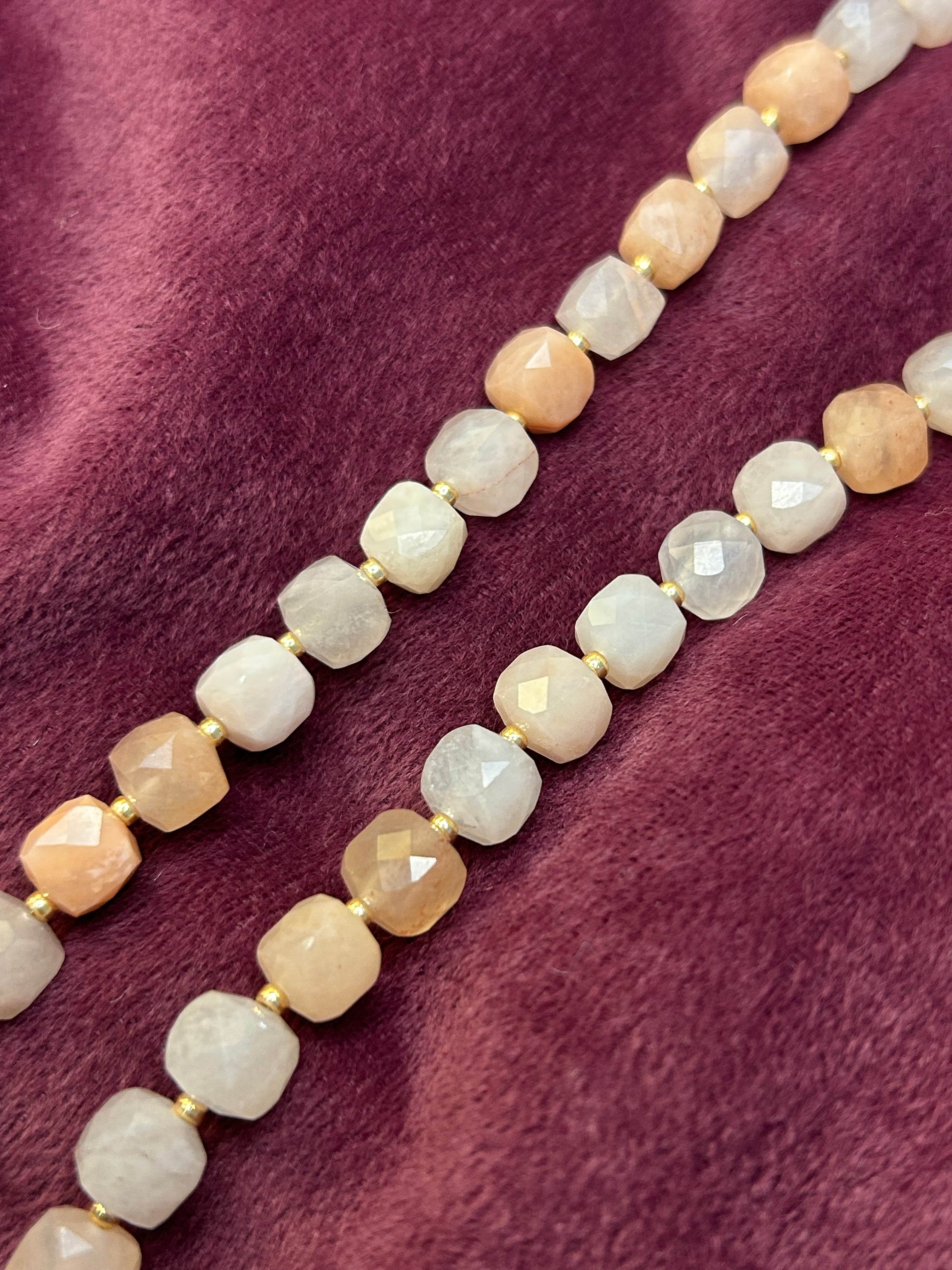 Necklace with beige and white beads on a purple fabric background