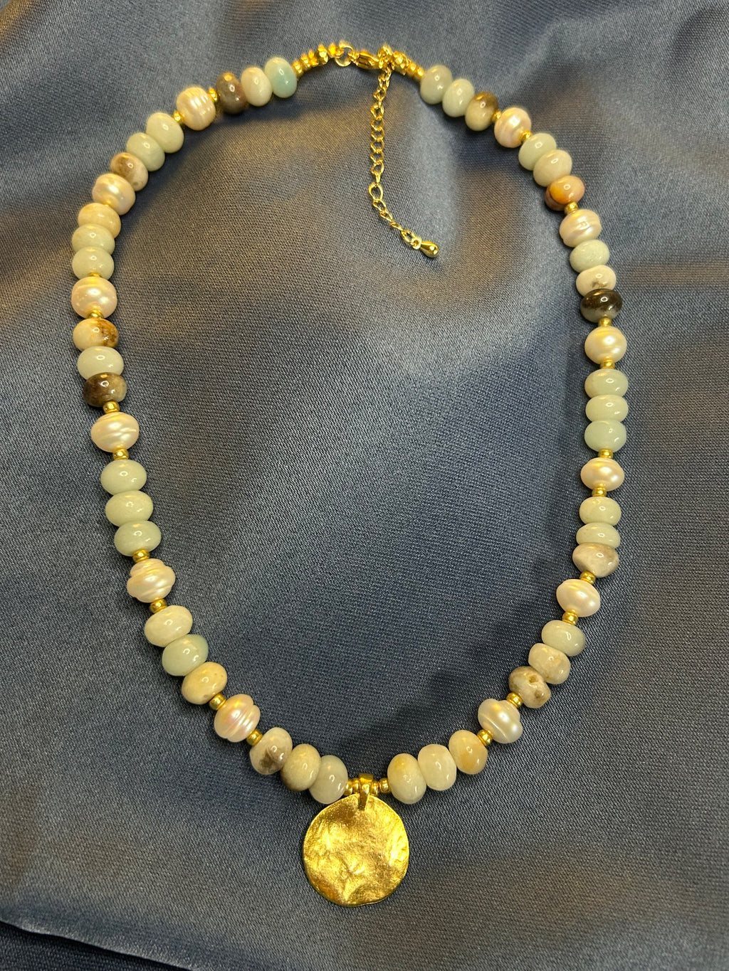 Necklace with beads and a gold clasp on a gray fabric background