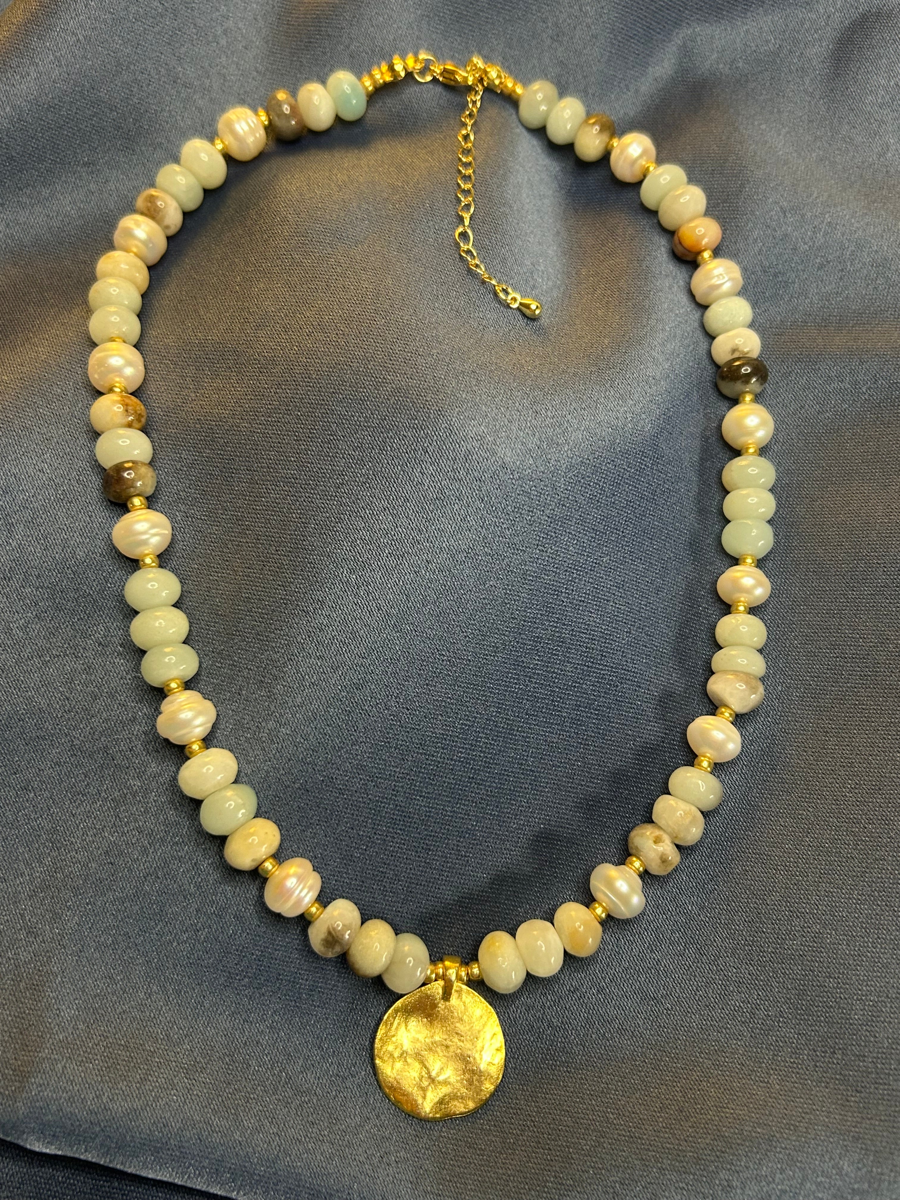 Necklace with beads and a gold clasp on a gray fabric background