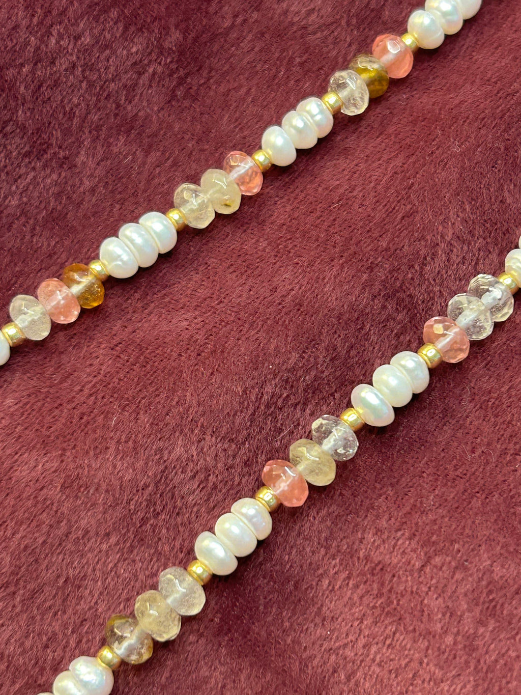 Necklace with multicolored beads on a maroon fabric background