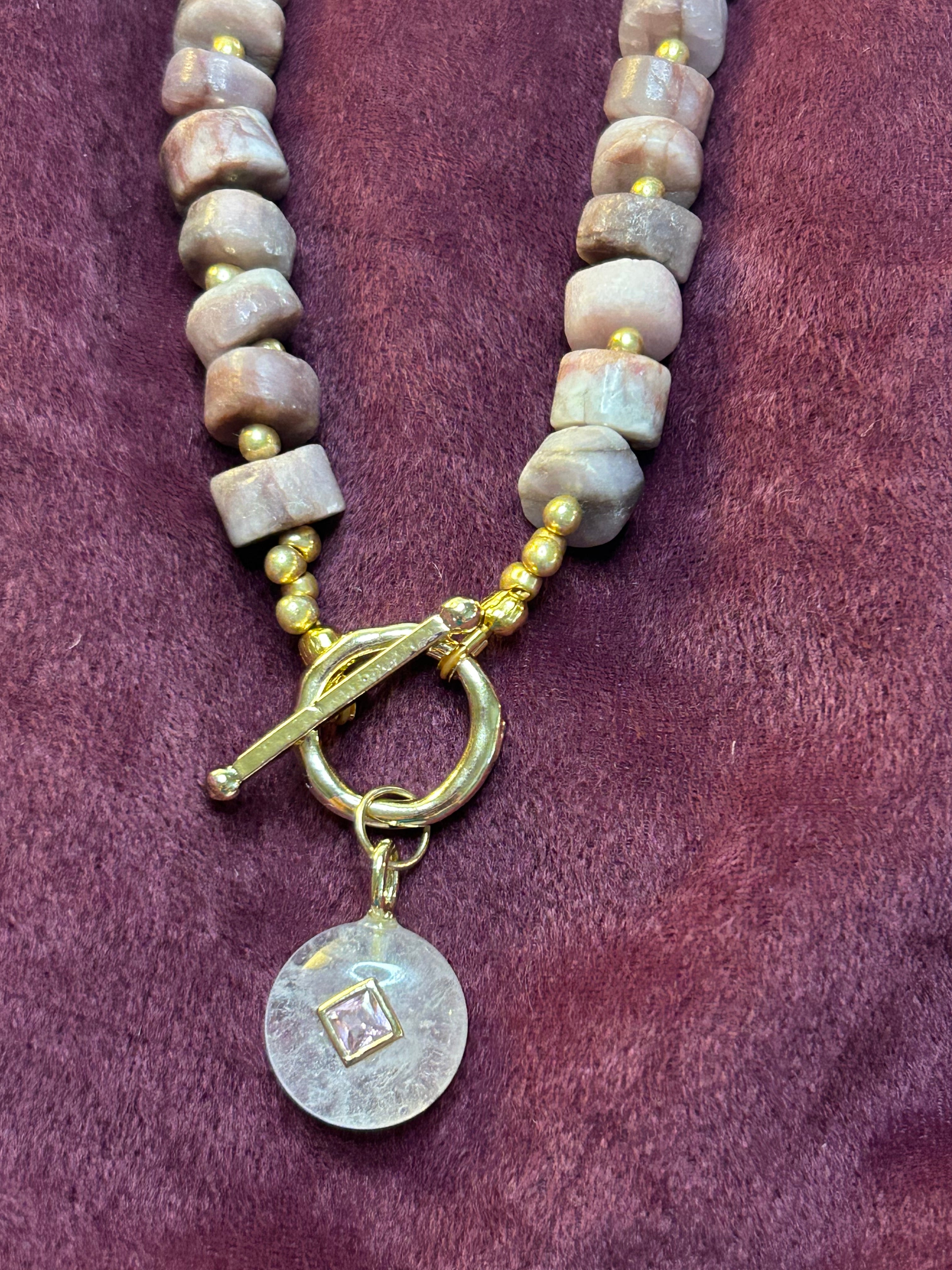 Necklace with beaded chain and decorative clasp on a purple fabric background