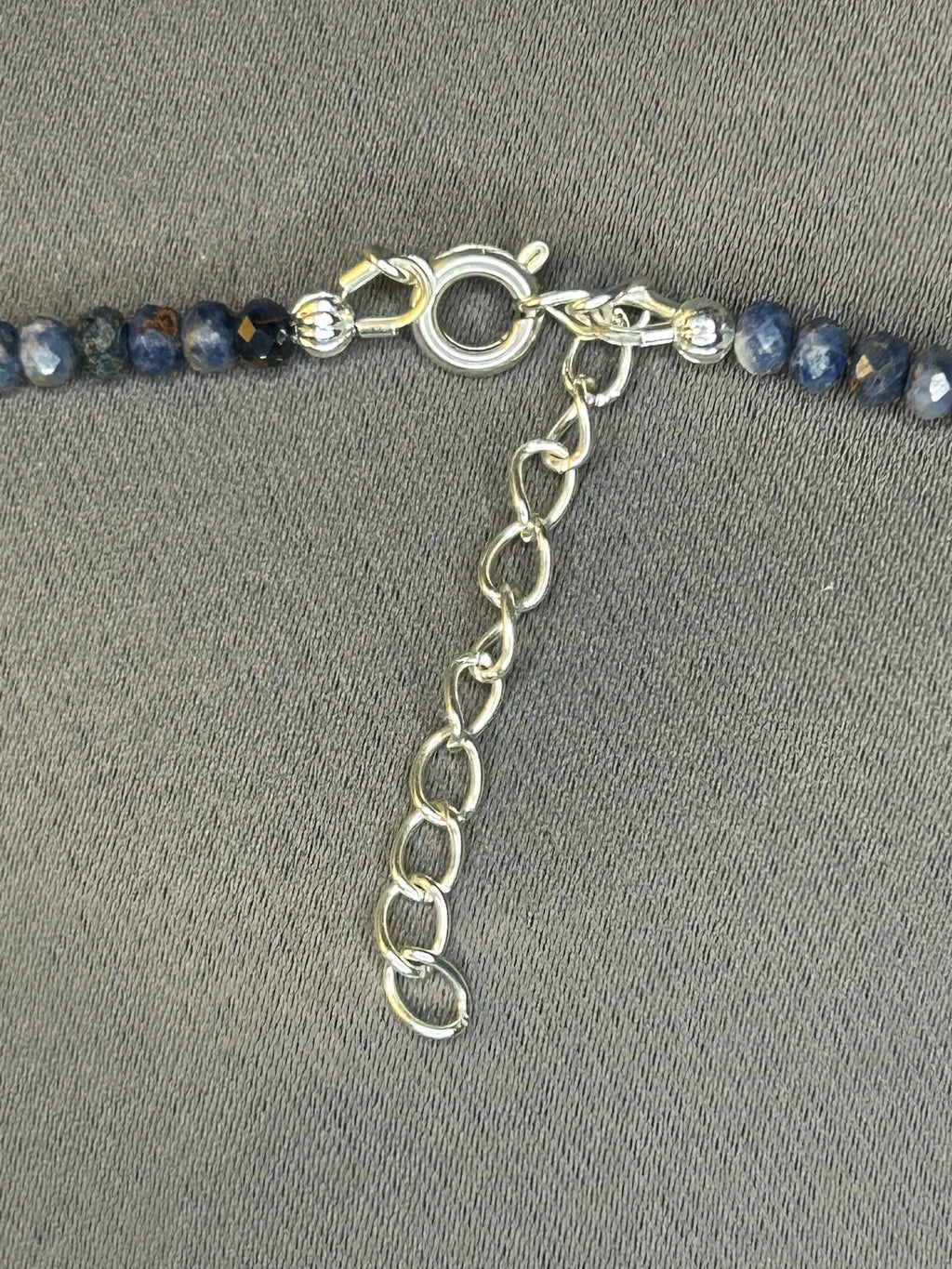 Close-up of a beaded necklace with a silver clasp on a gray background
