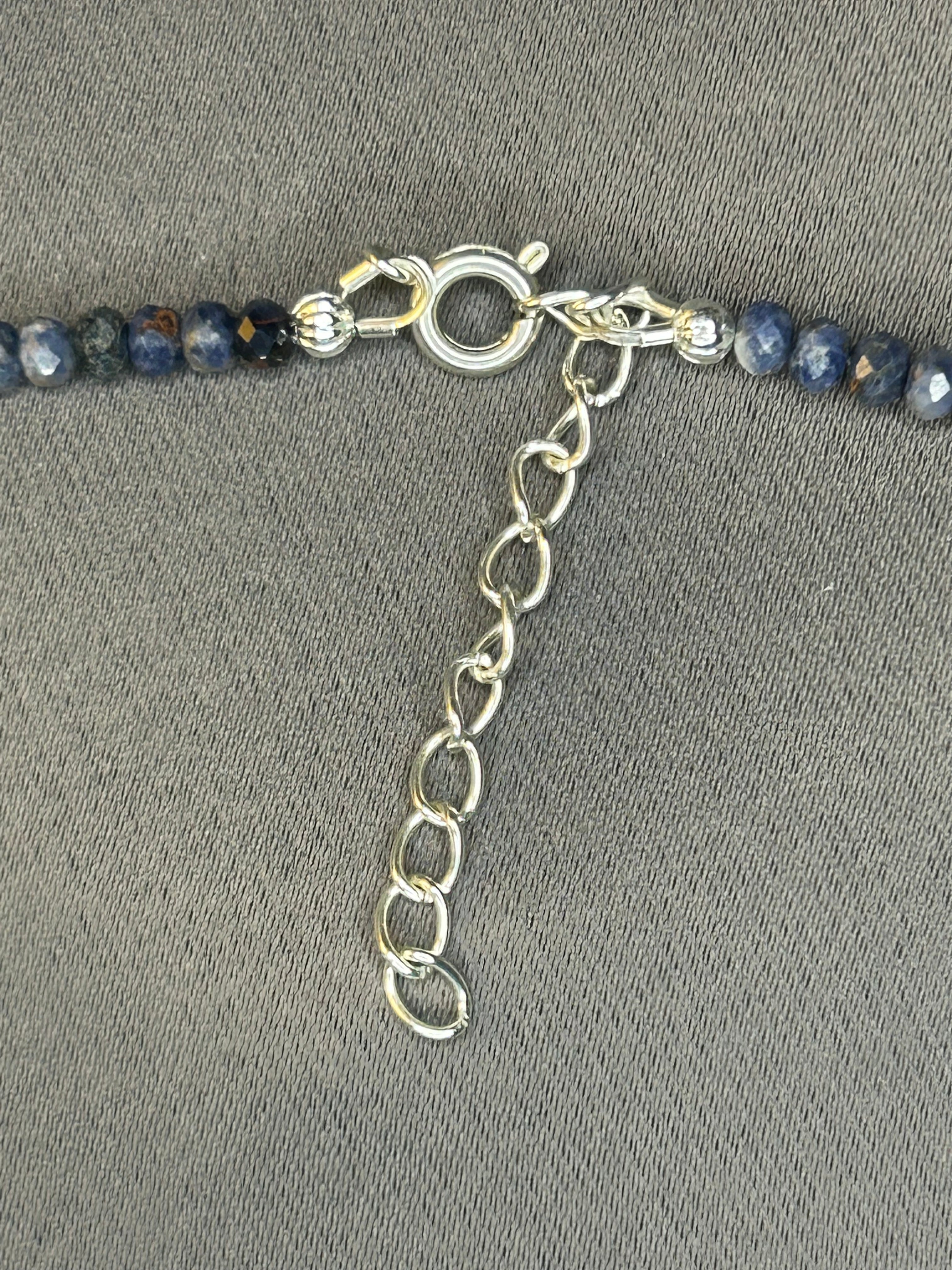 Close-up of a beaded necklace with a silver clasp on a gray background