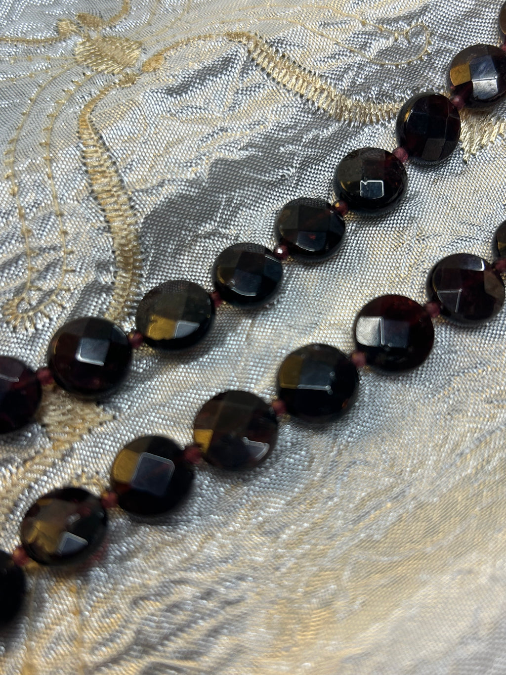 Necklace with dark beads on a textured fabric background