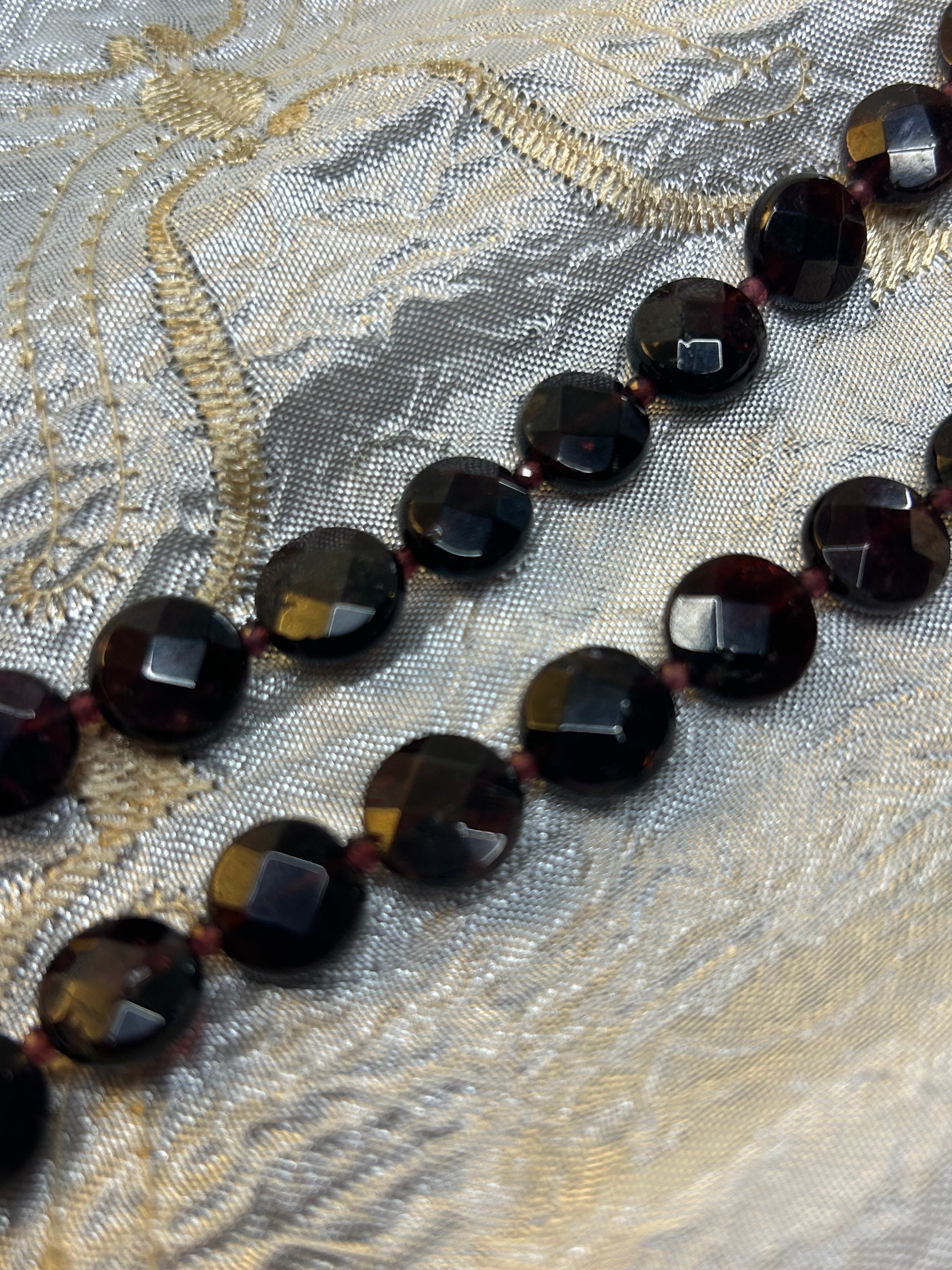 Necklace with dark beads on a textured fabric background