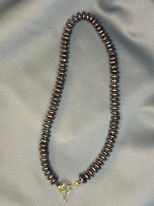 Beaded necklace with a gold clasp on a gray fabric background