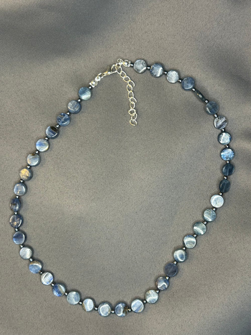 Necklace with blue beads and chain on a beige background
