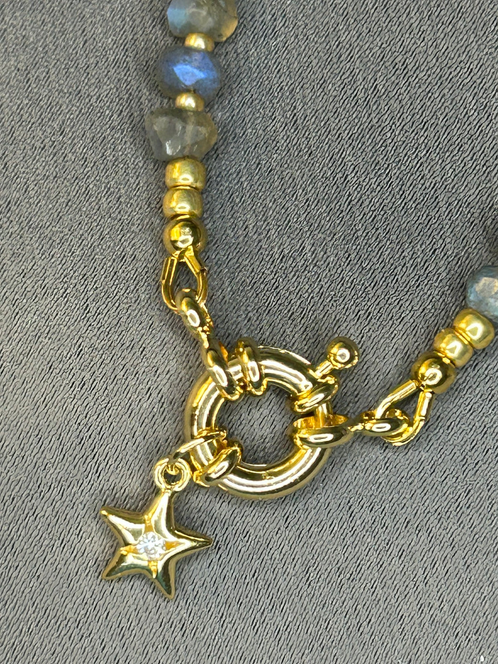 Gold clasp with star charm on a gray background