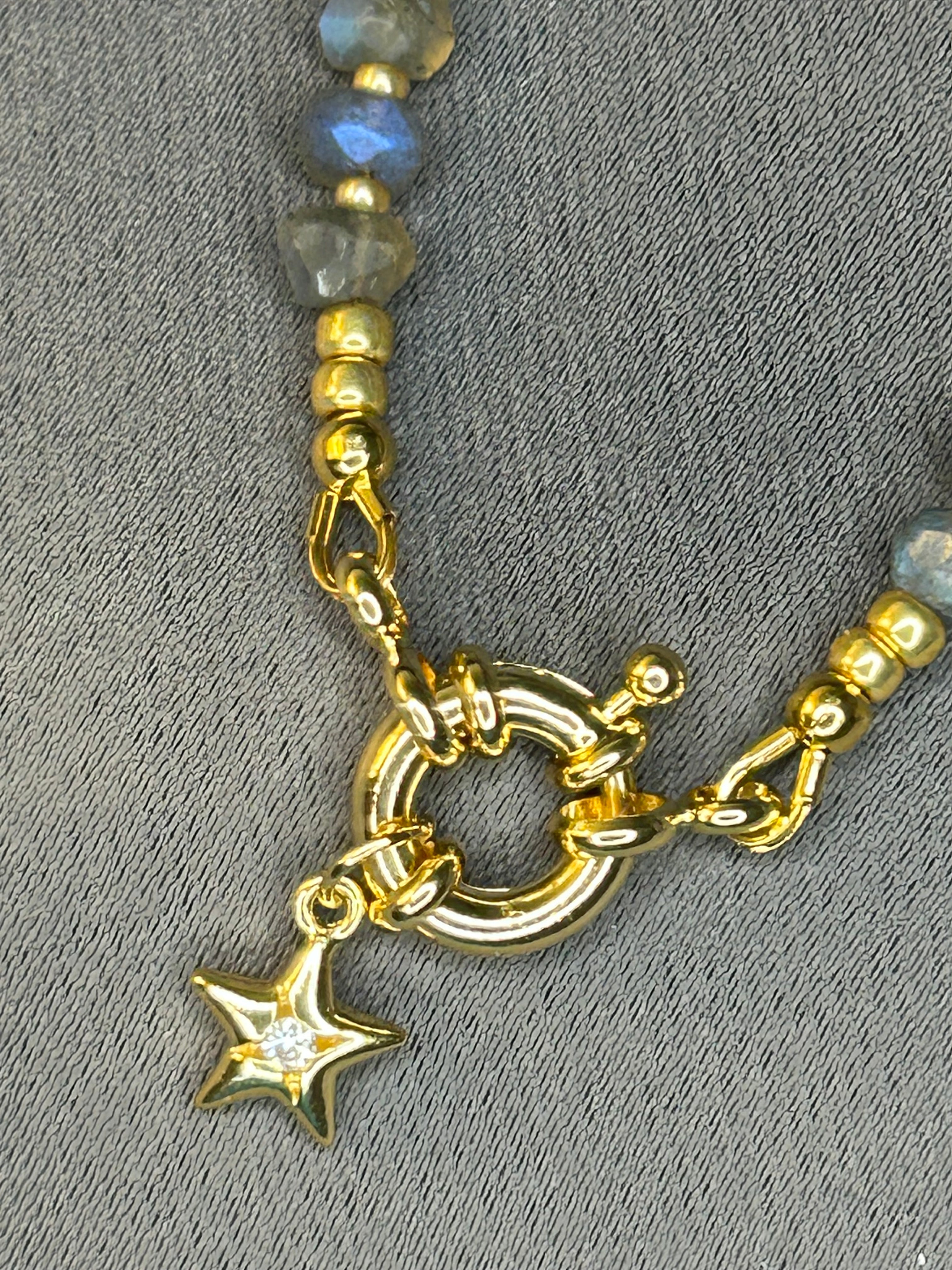 Gold clasp with star charm on a gray background