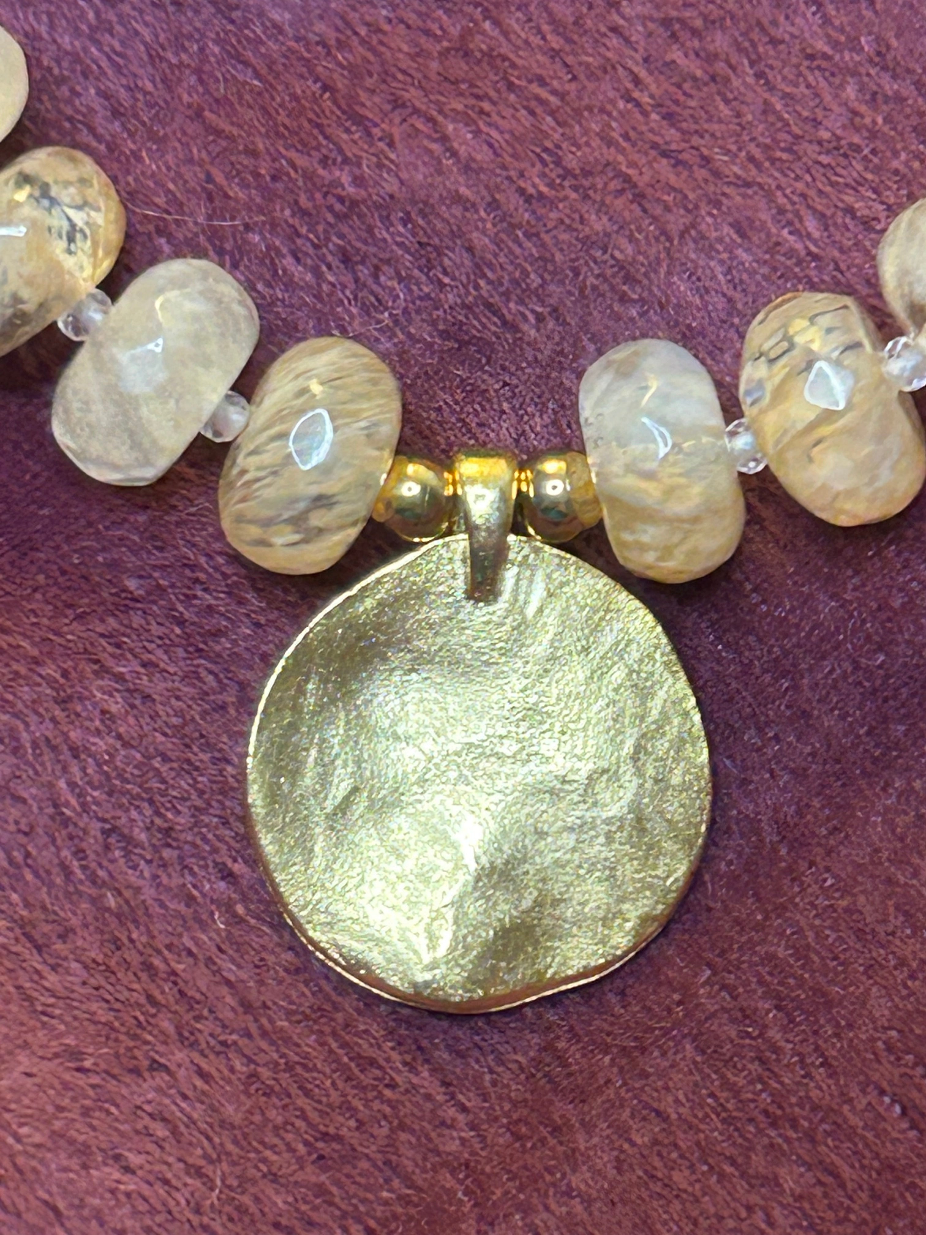 Close-up of a necklace with gold and beige beads on a purple background
