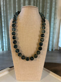 Green beaded necklace on a mannequin bust with a neutral background