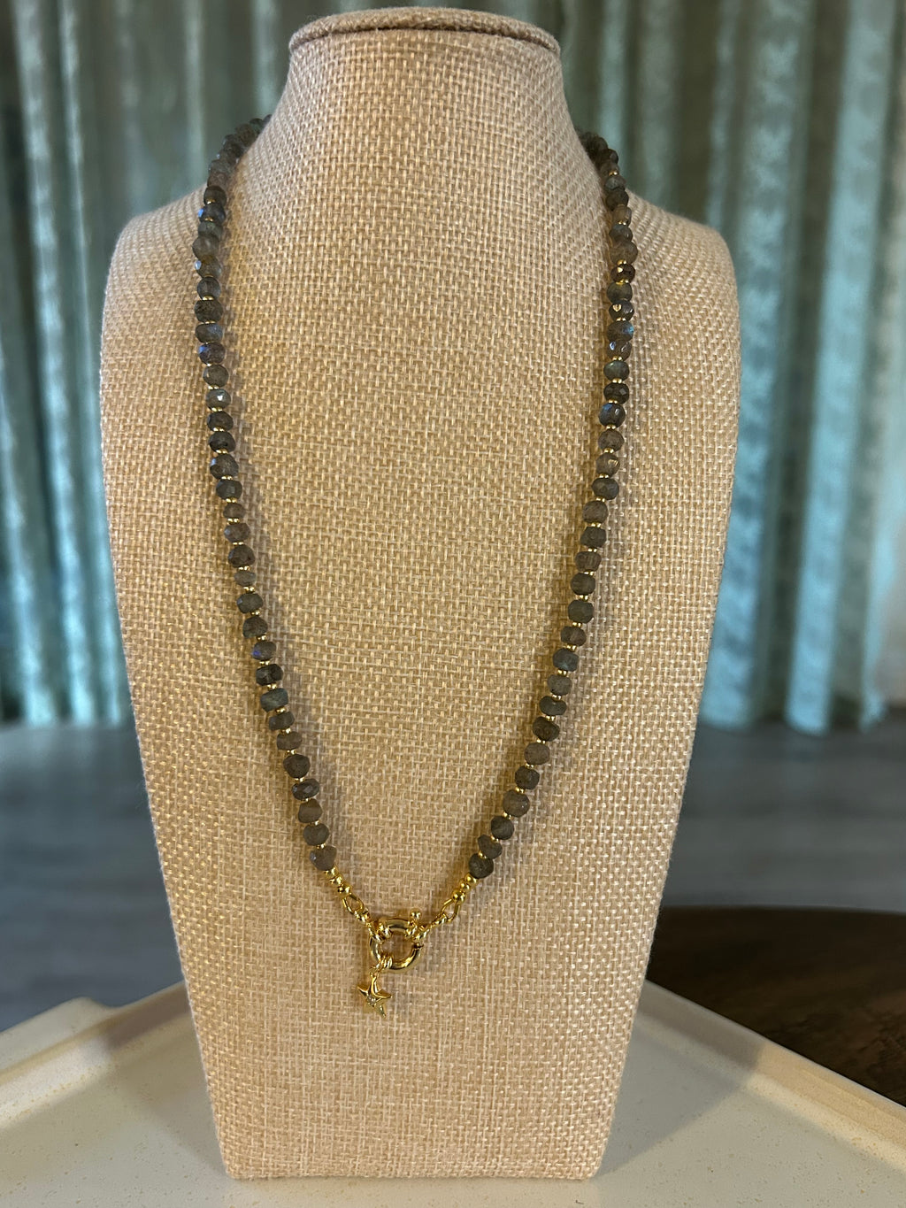 Necklace on a beige display stand with a neutral background