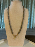 Necklace on a beige display stand with a neutral background