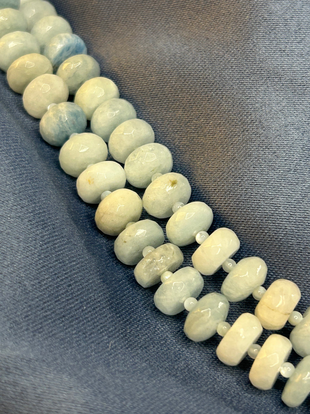 Necklace with light-colored beads on a gray fabric background