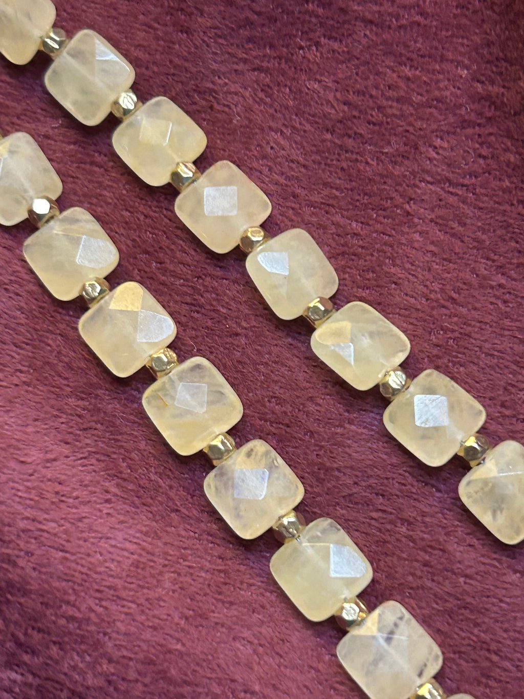 Necklace with square-cut stones on a maroon background