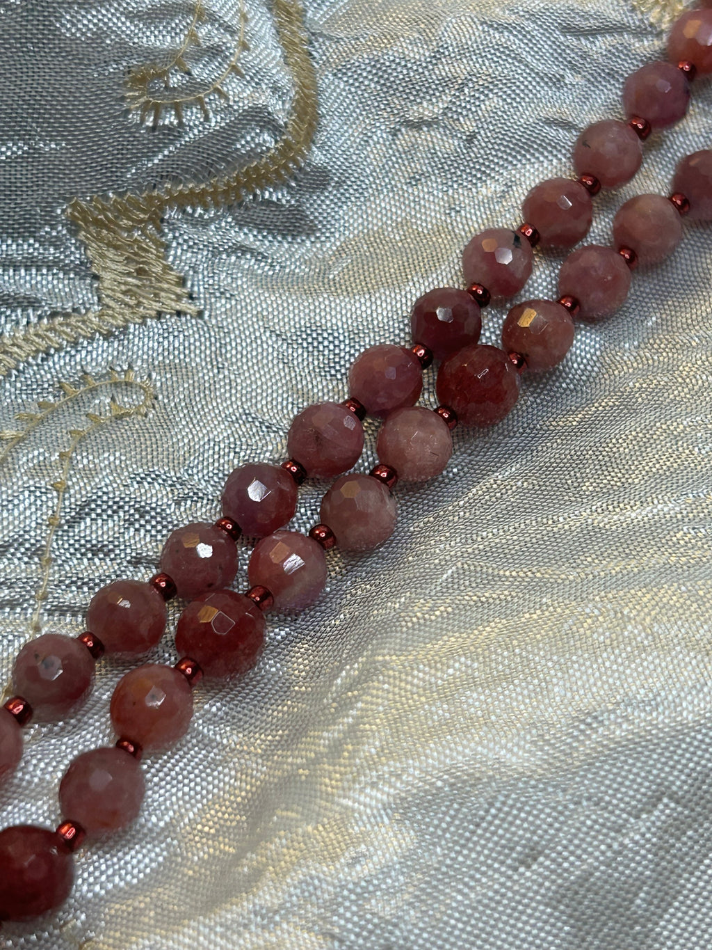 Necklace with red beads on a textured fabric background