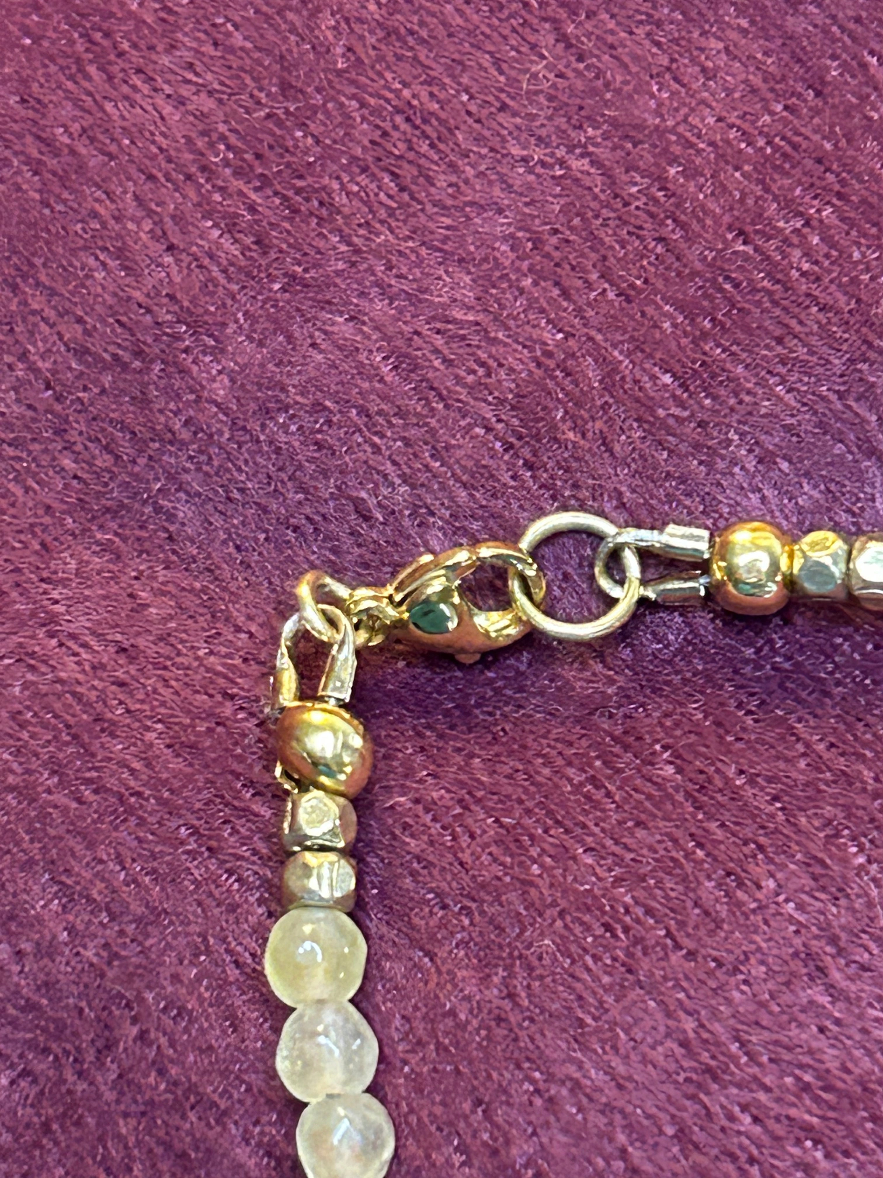 Close-up of a beaded necklace with gold elements on a purple fabric background