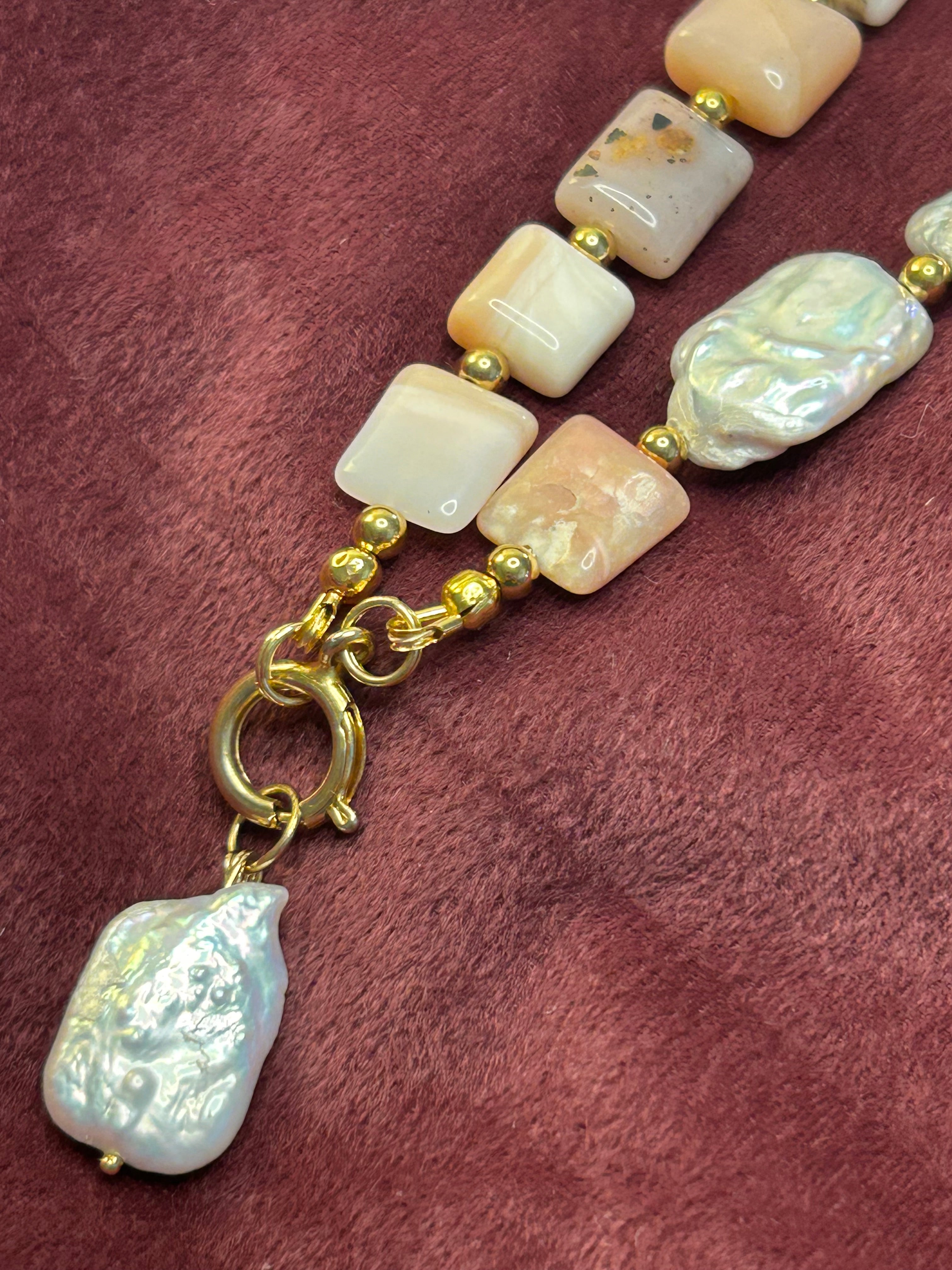 Beaded necklace with gold clasp on a maroon fabric background